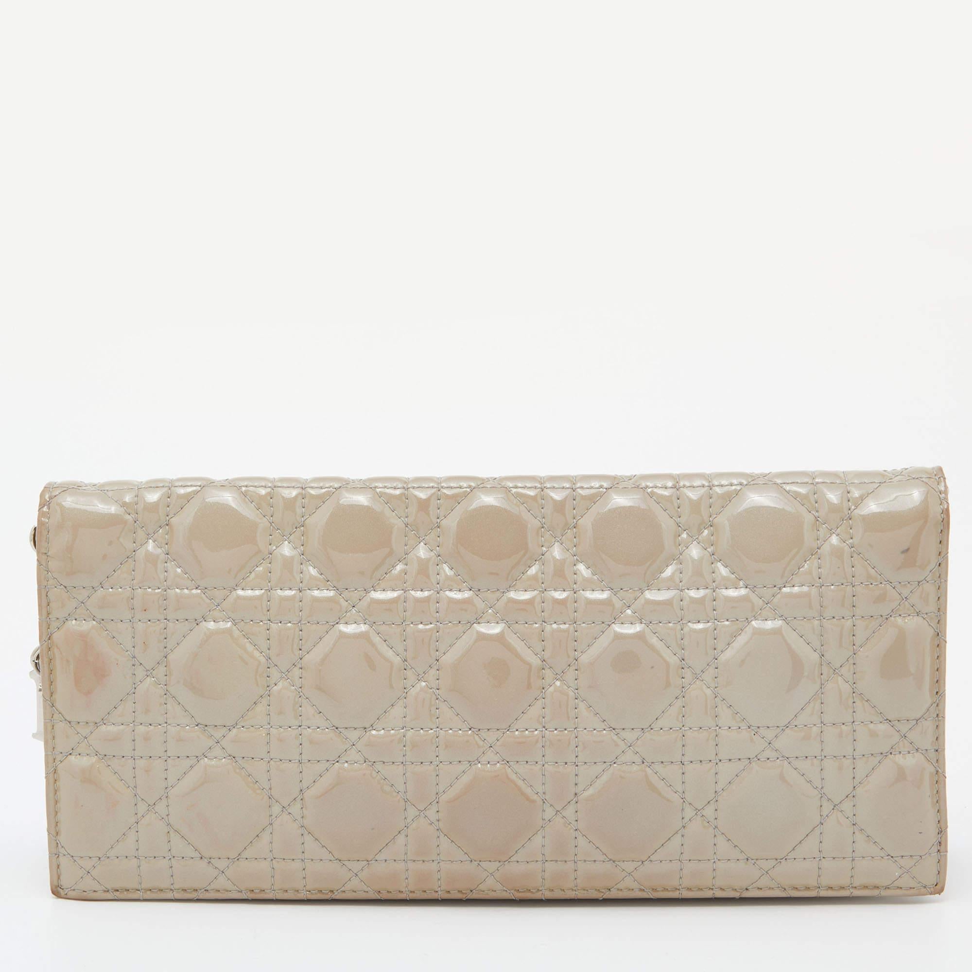 This Lady Dior clutch is a coveted creation that every fashionista craves to possess. This grey beauty has been crafted from patent leather and it carries the signature Cannage pattern. It is equipped with a nylon interior and complete with dangling