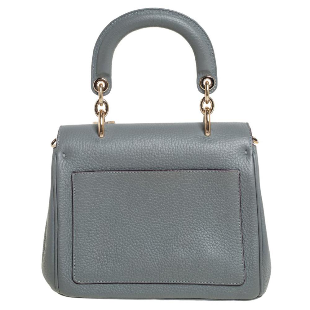 Flap bags as gorgeous as this one from Dior will never go out of style. This mini Be Dior bag has a lovely silhouette and a chic appeal. It has been meticulously crafted from leather and equipped with a single rolled top handle, protective metal