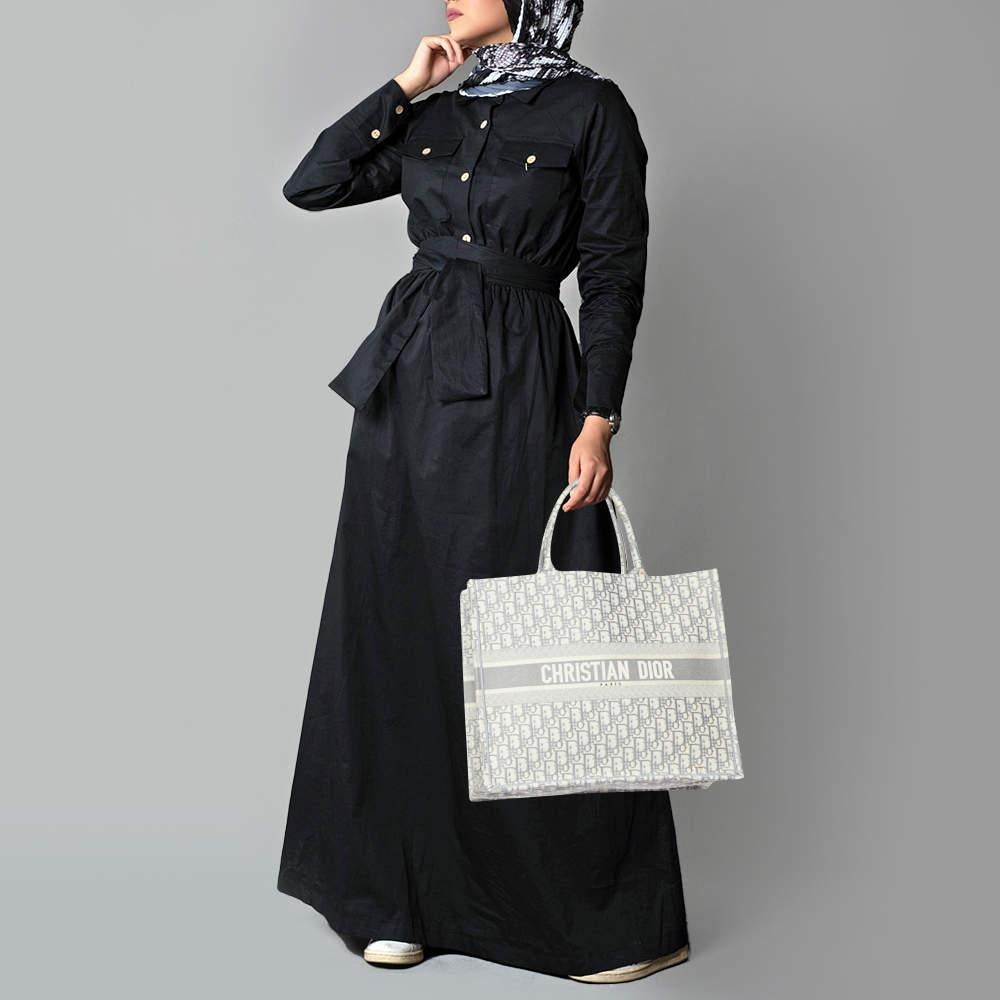 Designed by Maria Grazia Chiuri  the Dior Book Tote is a travel accessory for people with style. The bag here is crafted using canvas into a beautiful structure and is covered in the Oblique motif. Two handles  the Christian Dior signature  and a