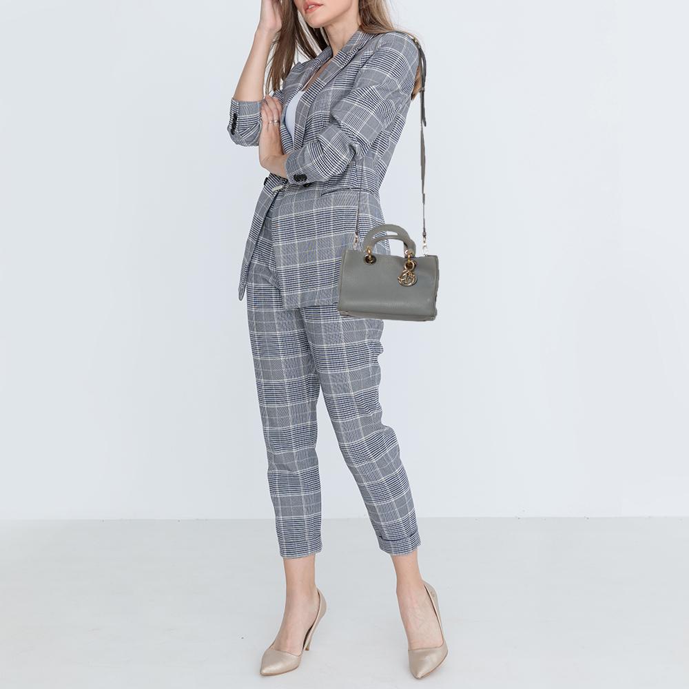 The Diorissimo tote from Dior is a piece that has never gone out of style. The pebbled leather bag comes in a grey shade with opulent hardware and Dior letter charms. It comes with dual top handles and protective feet at the bottom. A snap button