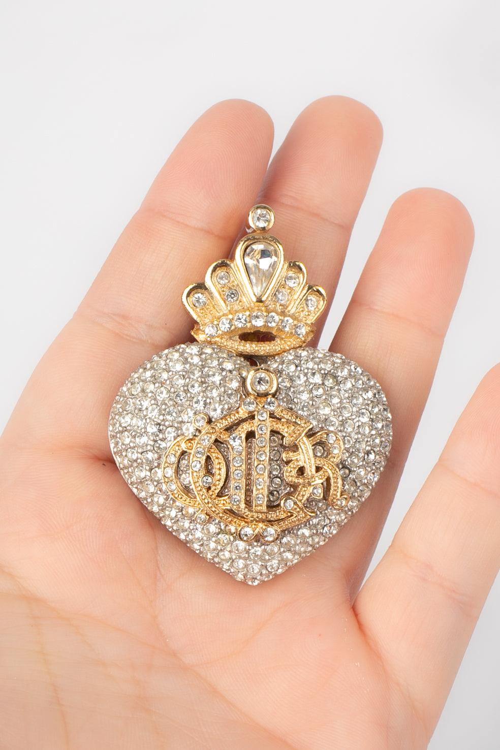Dior - (Made in France) Silvery and golden metal brooch representing a heart topped with a crown and entirely ornamented with rhinestones.
 
 Additional information: 
 Condition: Very good condition
 Dimensions: 5.5 cm x 4.5 cm
 
 Seller Reference: