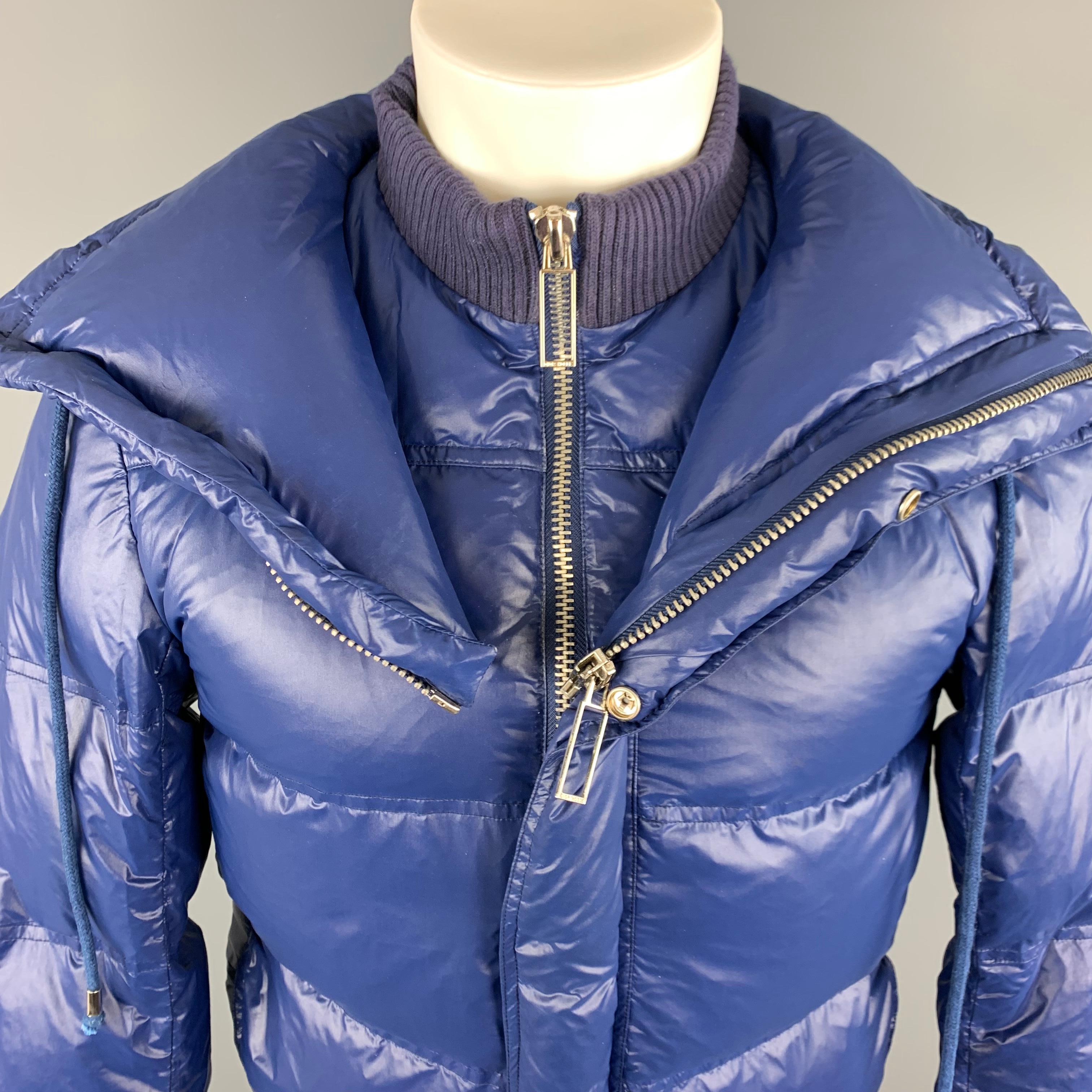 DIOR HOMME Down Filled Puffer Jacket comes in a blue tone, solid polyamide material, with zipper, snaps and drawstring at closure, zip and slit pockets and ribbed cuffs and hem. Features an additional zipper closure to transform the puffer jacket to