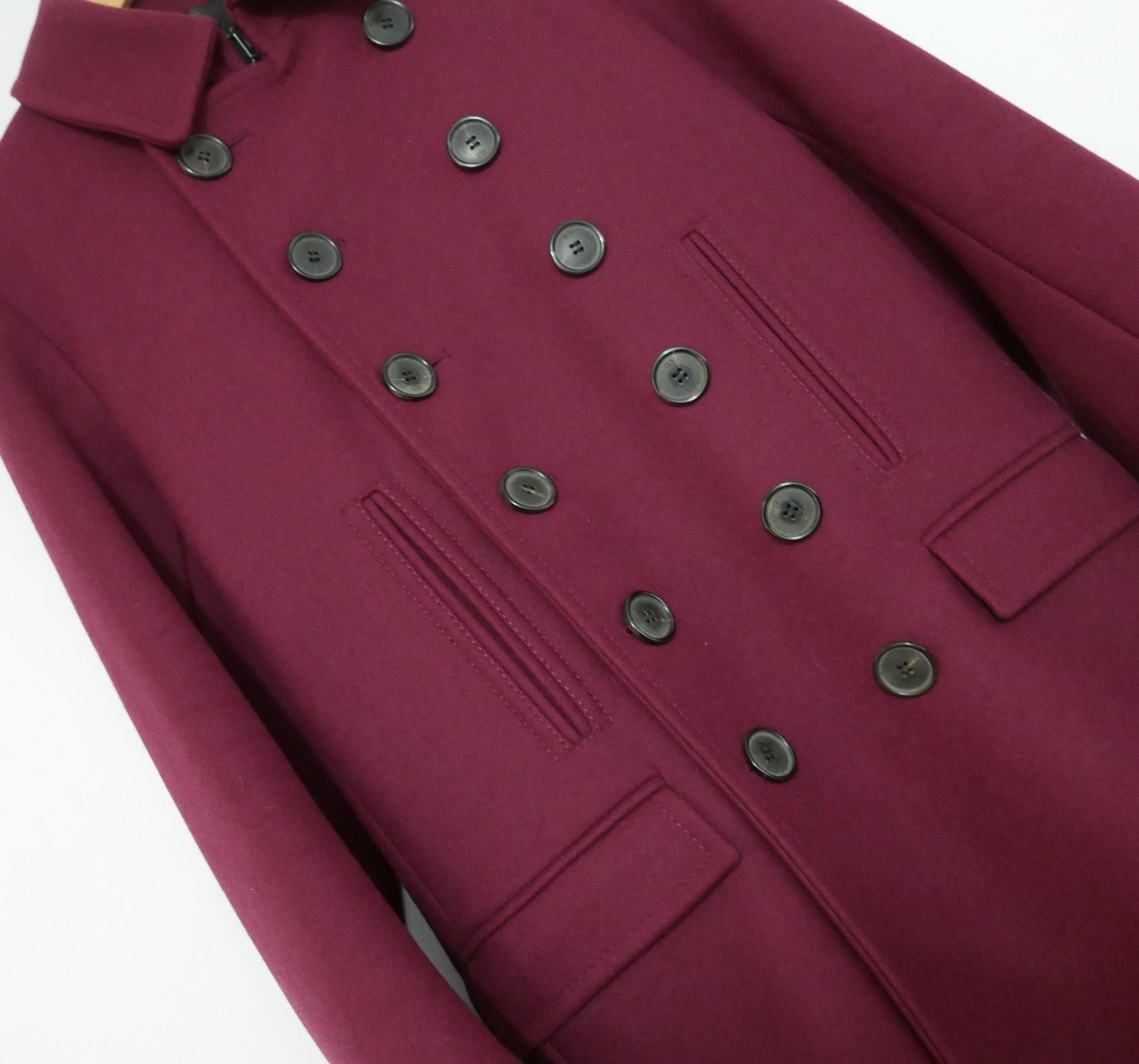 Superbly crafted, luxe coat from the Dior Homme Fall 2013 Collection. Bought for over £2500 and unworn. Made from heavy, thick burgundy wool with a black satin lining. It has a sleek lined breasted front with large CD etched buttons, hook front
