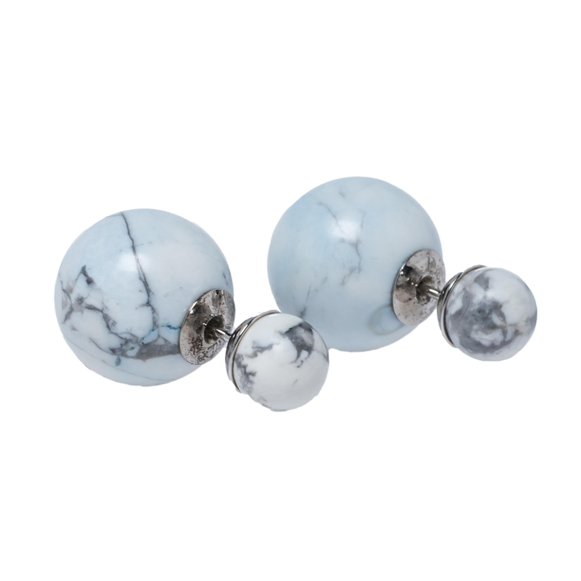 These Tribales stud earrings by Dior flaunt a stylish and luxurious appearance and come in ivory and blue hues. These earrings showcase a small stud that sits on the ear while the larger one peeks out from behind the lobe. They are detailed with a