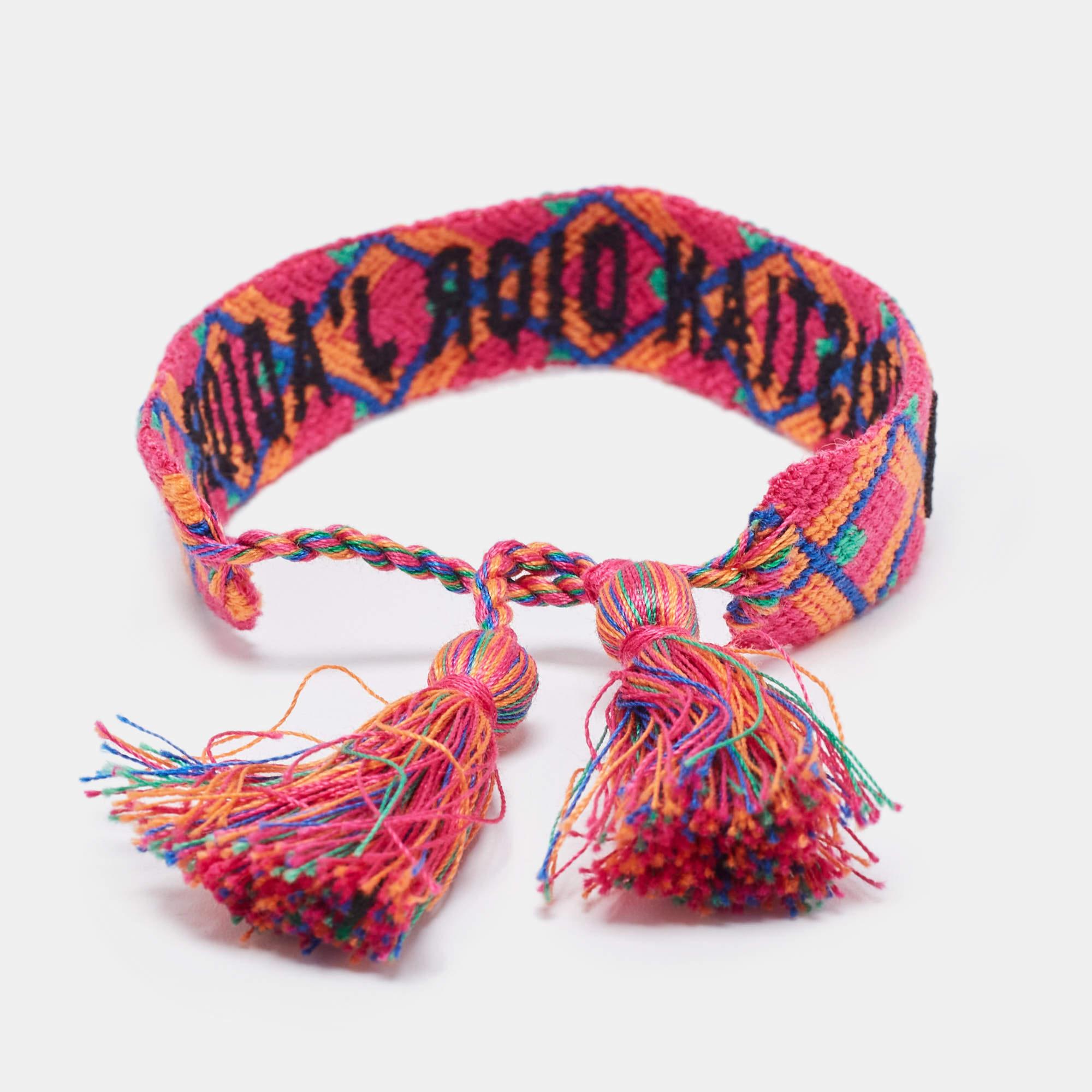 Das J'adior-Armband wird durch das Zusammenweben verschiedener Baumwolltöne hergestellt. Das Armband ist ein echter Hingucker und angenehm zu tragen. Das Band ist mit dem Schriftzug des Hauses verziert und mit Quastenbändern versehen.

