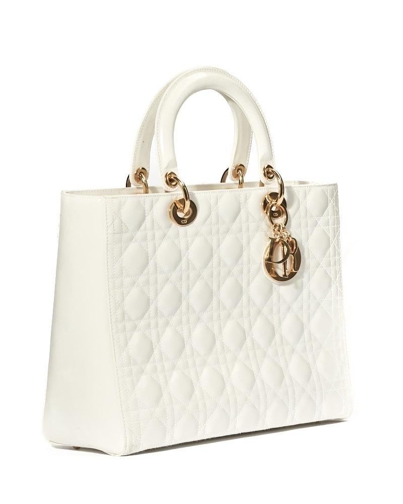 Borsa firmata Dior, linea Vintage, modello Lady nella misura large, realizzata in pelle verniciata bianca con motivo cannage e hardware dorato. Dotata di una chiusura superiore a zip, internamente rivestita in tela logata beige con comoda tasca, la