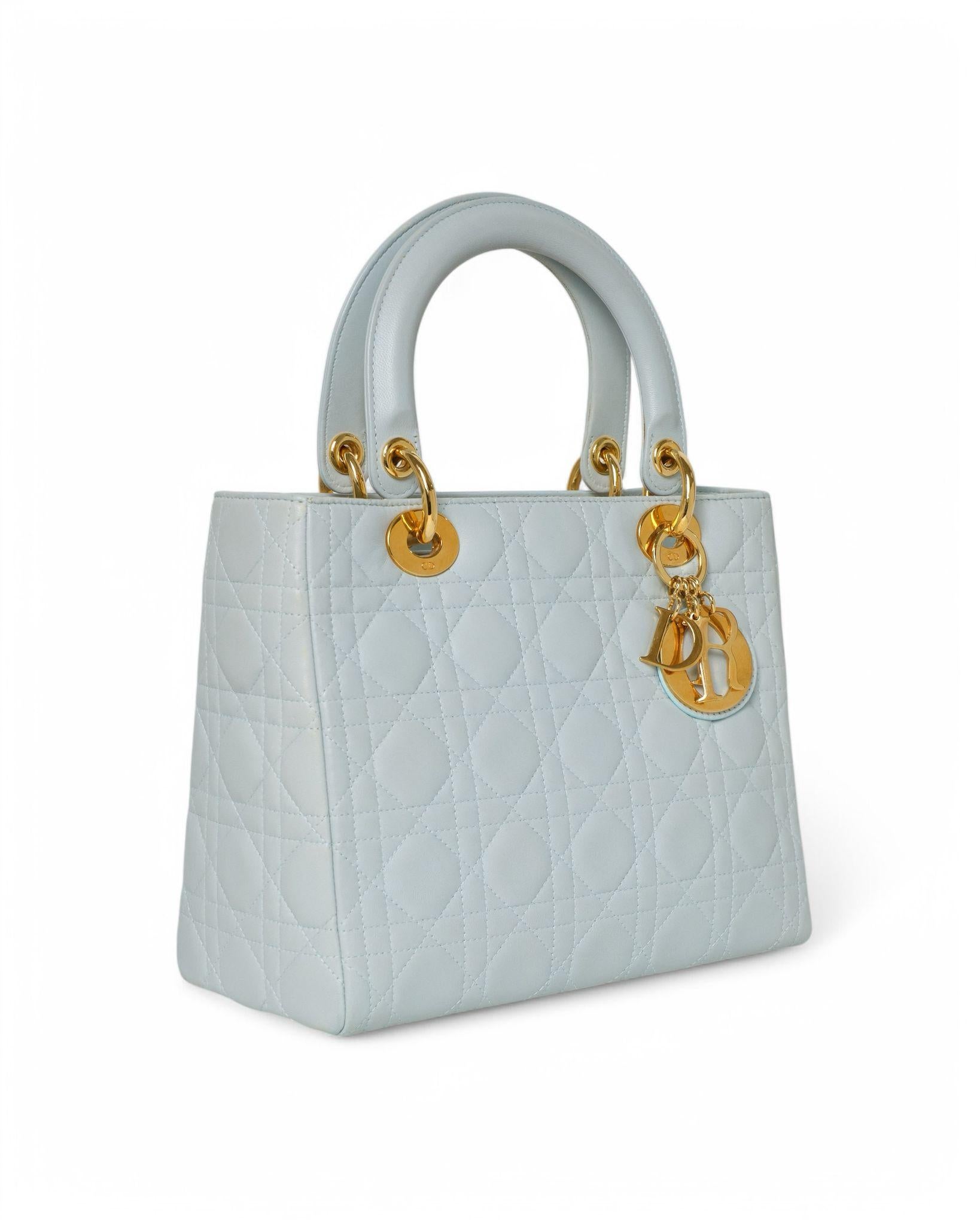 Borsa firmata Dior, modello Lady Vintage, misura Medium,  realizzata in pelle Cannage azzurra con dettagli in hardware oro. Dotata di una chiusura con zip, l’interno è rivestito in tela  logata  tono su tono  e offre una comoda tasca per una facile