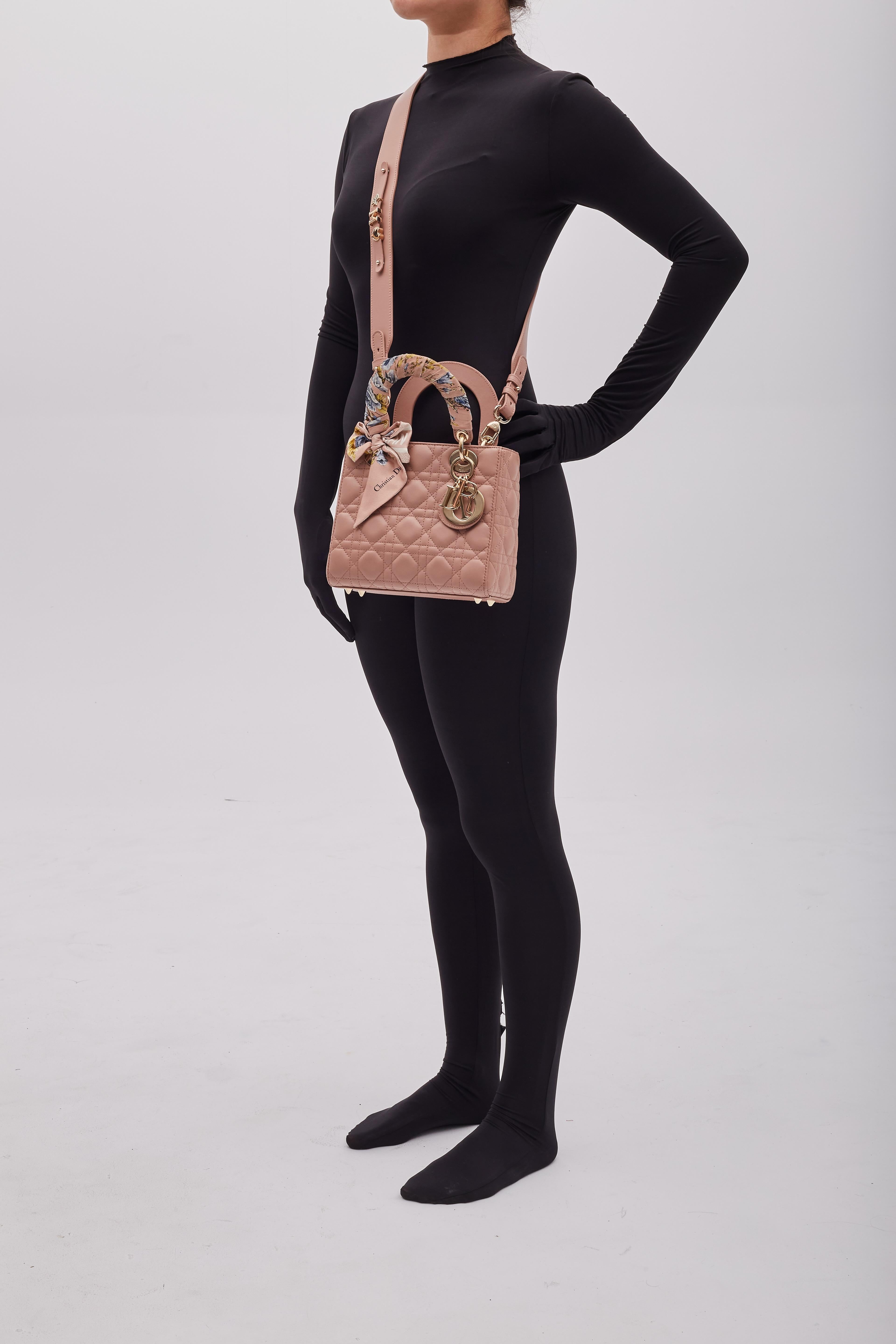 Diese Tasche ist aus gestepptem Lammleder in zartem Rosa gefertigt. Die Tasche hat einen breiten Schulterriemen und Griffe aus Leder mit polierten, hellgoldenen Beschlägen und einem hängenden Charme mit Dior-Initialen. Der Deckel öffnet sich zu