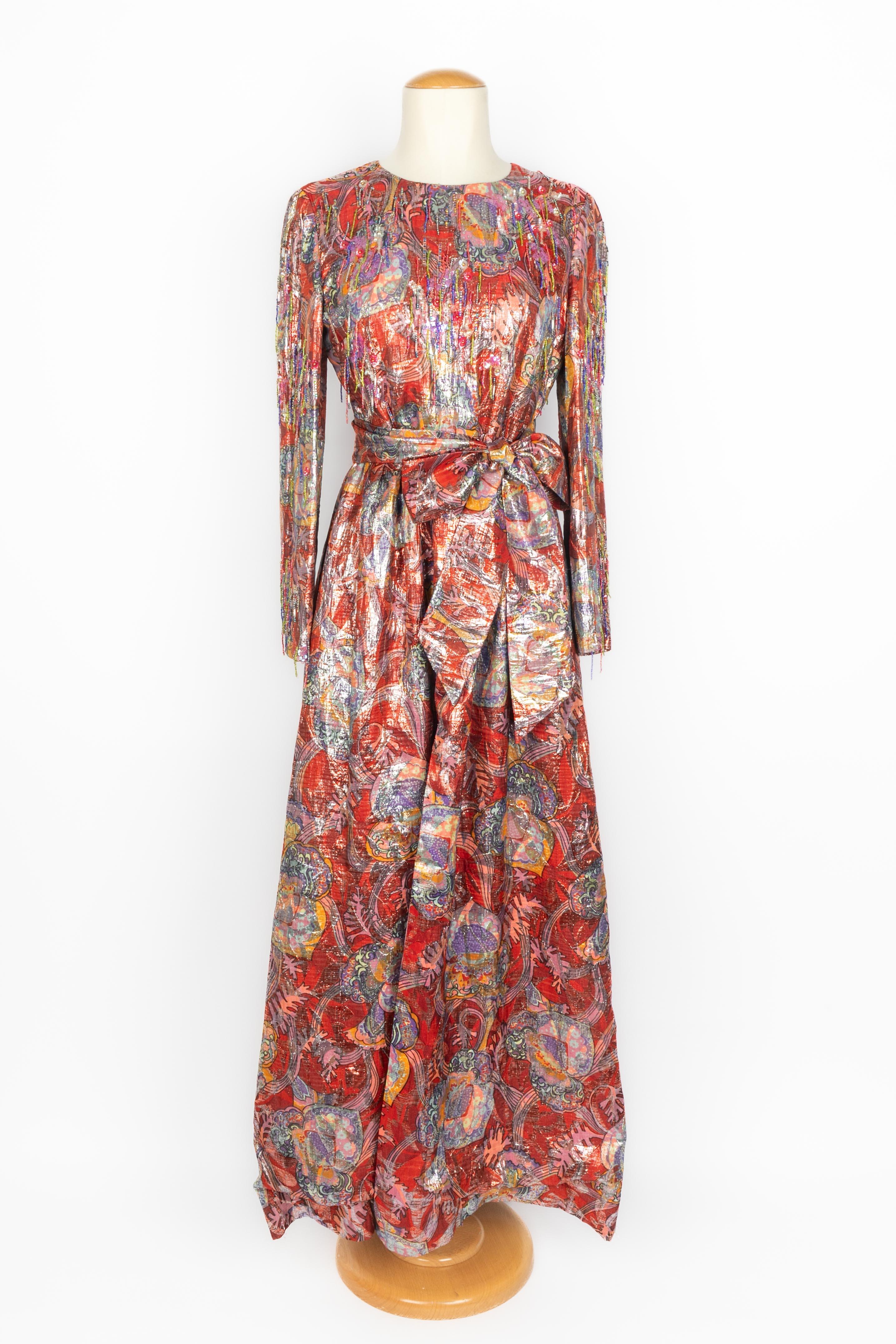 DIOR - (Made in France) Long purple and red lamé dress with long sleeves and sewn with pearl and sequin fringes. It comes with a belt, and it has a front split. Composition and size labels missing, it fits a 38FR. Piece from the