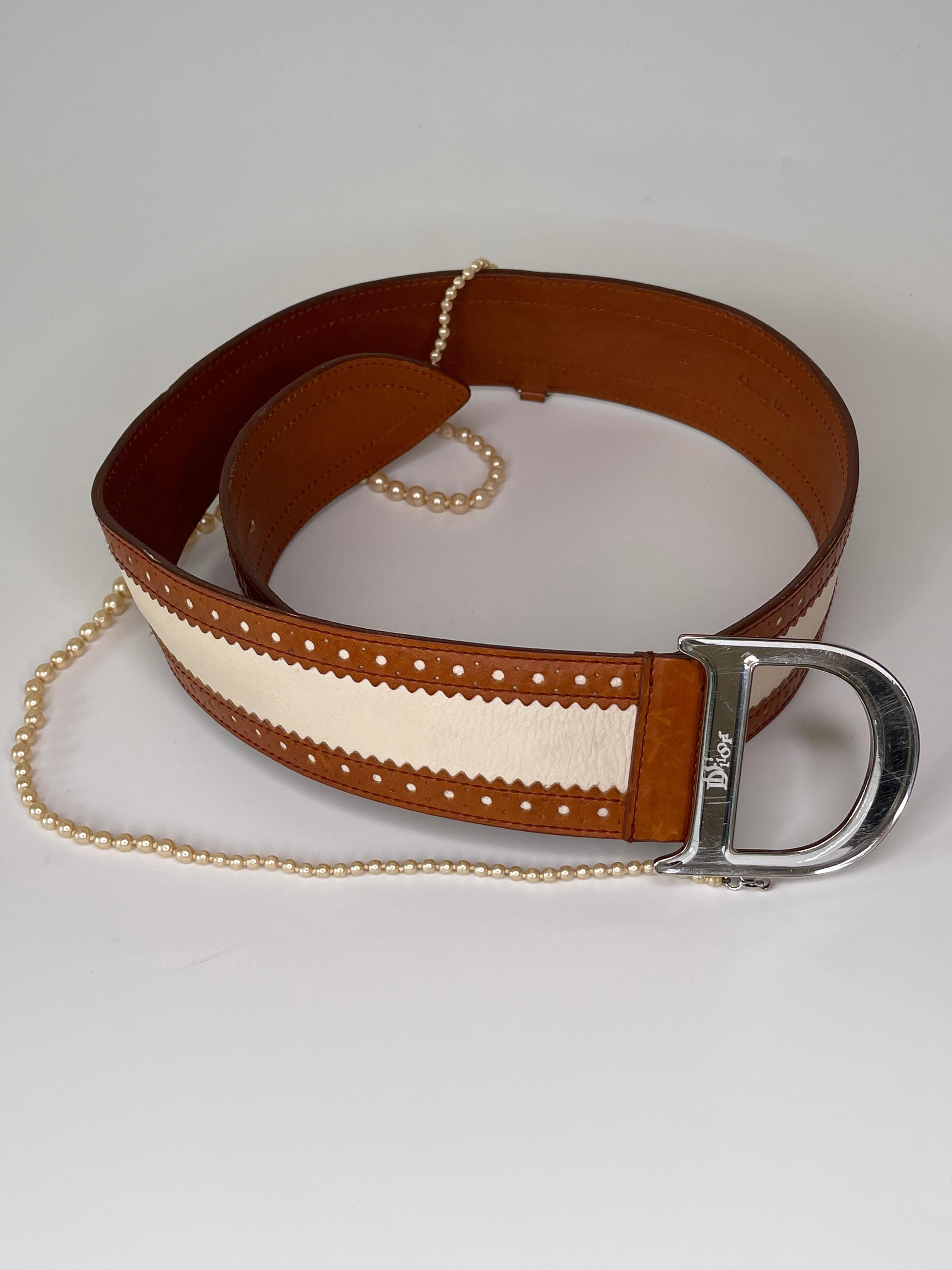 This Dior Detective Pearl Belt consists of a fashionable leather design with a silver mirrored buckle, and a pearl chain attached.

COLOR: Beige, silver mirrored buckle 
MATERIAL: Leather, faux pearl chain
ITEM CODE: 15 BM-0054
MEASURES: L 37” x W