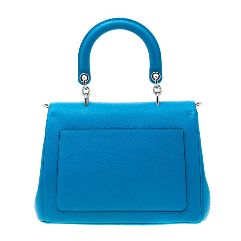 Flap bags as gorgeous as this one from Dior will never go out of style. This small Be Dior bag has a lovely silhouette and a chic appeal. It has been meticulously crafted from leather and equipped with a single rolled top handle, a removable