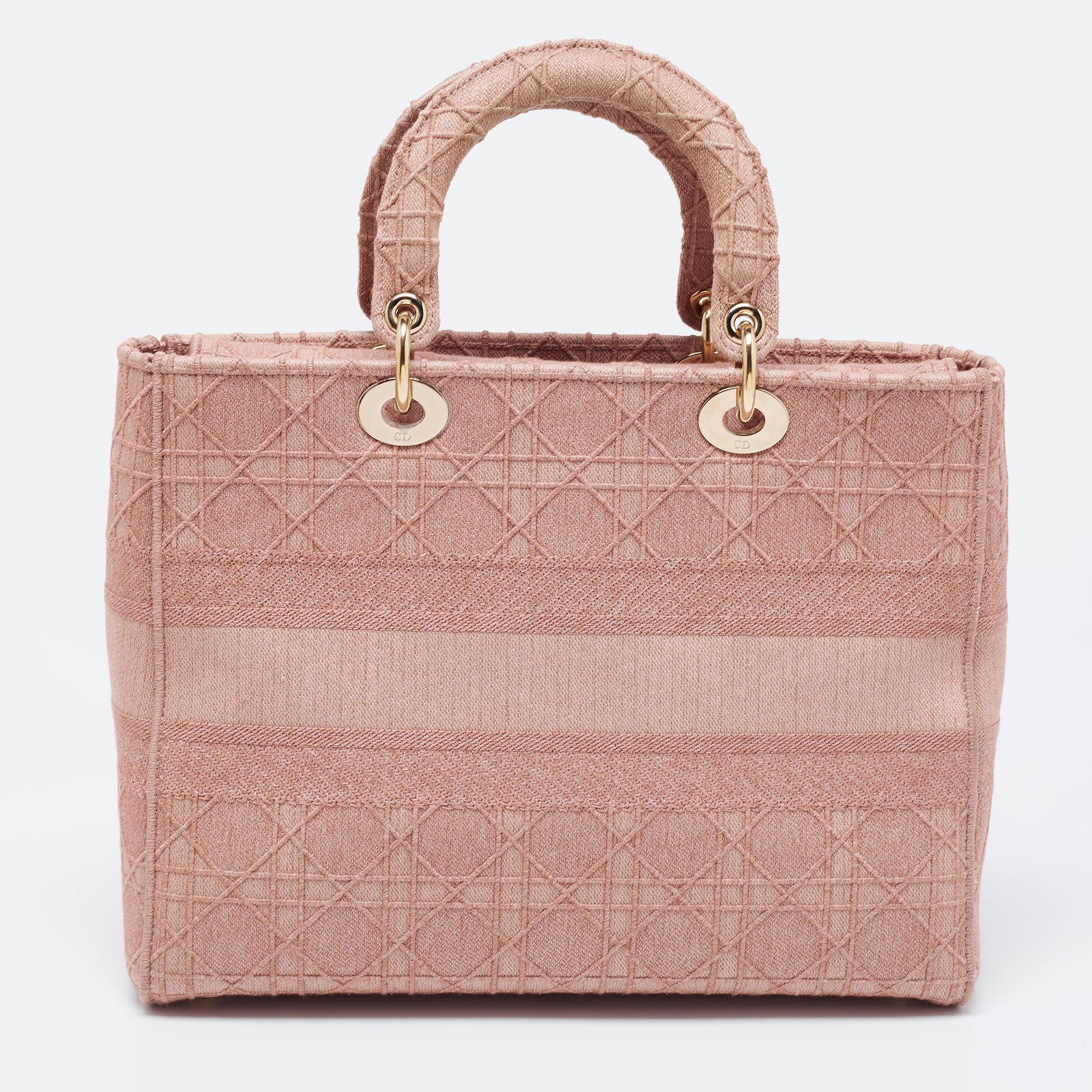 An iconic creation from the House of Dior, this Lady D-Lite tote brings eternal poise, gracefulness, and elegance to your appearance. This version comes crafted in light-pink Cannage-embroidered canvas, with gold-toned D.i.o.r charms attached to the