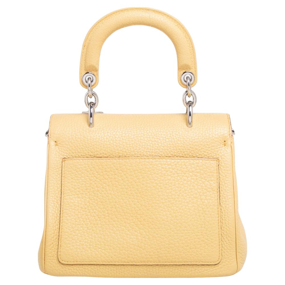 This mini Be Dior bag from the House of Dior is sure to add sparks of luxury to your wardrobe! It is crafted from light-yellow leather and features a chic silhouette. It flaunts a single top handle with attached 'DIOR' letter charms in silver-tone.