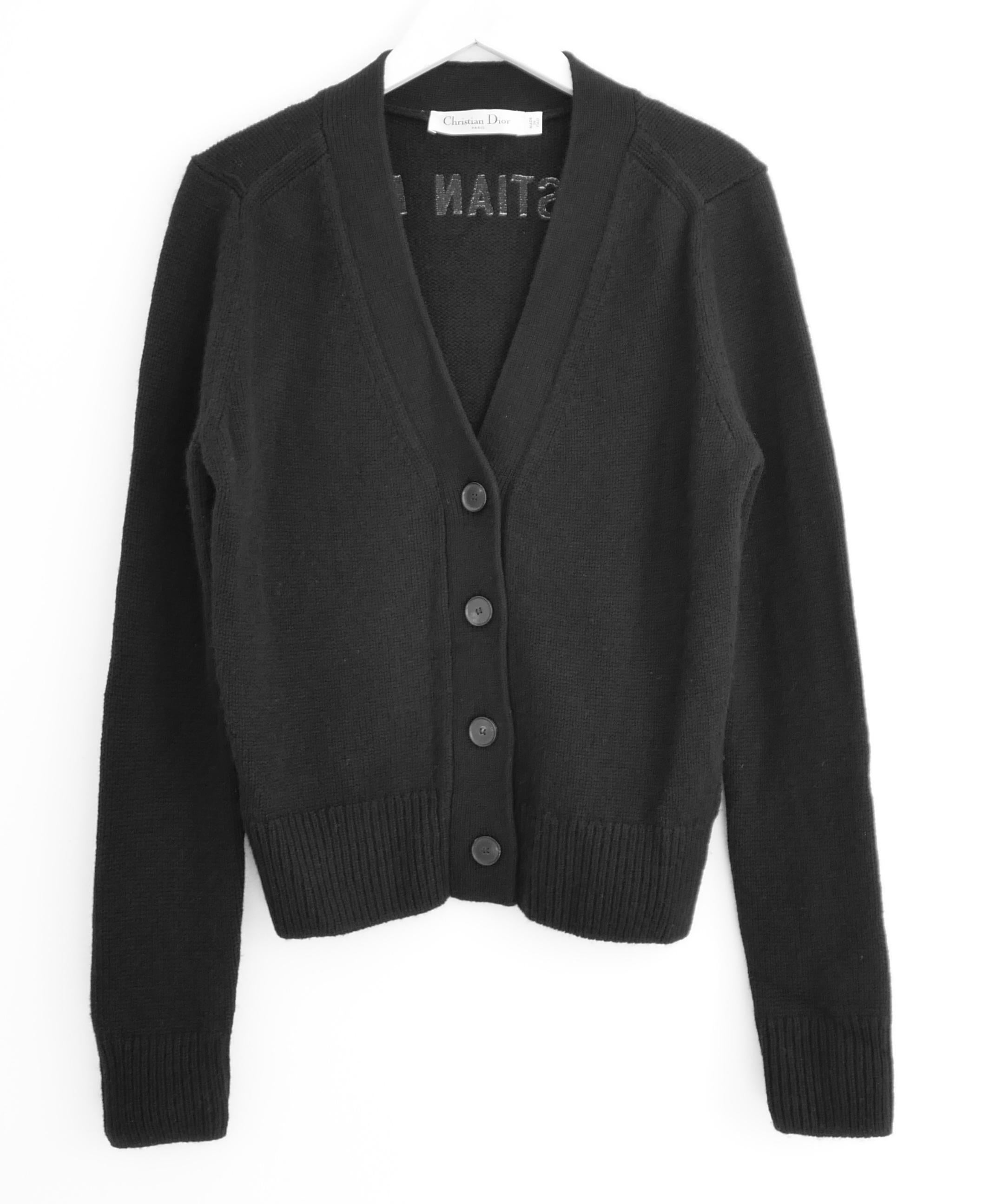 
Cárdigan de cachemira con logo trasero Dior de lujo moderno. Sin usar. De cachemira negra suave como un gatito, con el logotipo de Christian Dior bordado en la espalda. Tiene un corte relajado con escote en pico, remates de canalé y cierre de