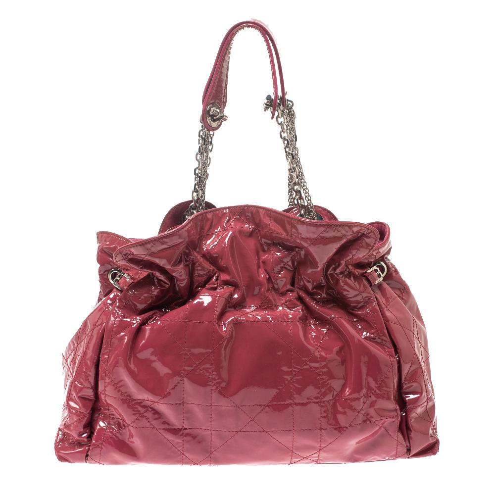 This stylish Le Trente hobo from Dior has been crafted from pink patent leather and styled with their signature cannage pattern. The bag features dual chain handles with leather shoulder rest, a CD cutout charm in slver-tone metal, a drawstring