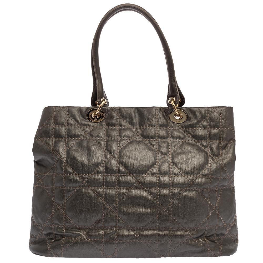 This soft tote from Dior is a timeless piece. The bag comes in a luxurious cannage leather exterior with gold-tone hardware and Dior letter charms. It features double top handles and protective metal feet at the bottom. The fabric-lined interior