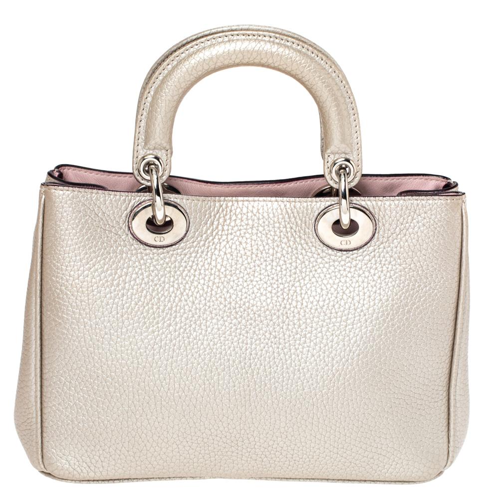 The Diorissimo tote from Dior is a timeless piece. The leather bag comes in a luxurious shade of metallic with silver-tone hardware and Dior letter charms. It features double top handles, a detachable shoulder strap and protective feet at the