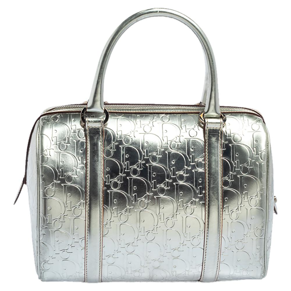This Boston bag by Dior sweetly embodies luxe elegance! Crafted from Oblique monogram leather, this metallic silver bag features a top zip closure that opens to a canvas interior, capable of accommodating all your daily essentials with ease. It is
