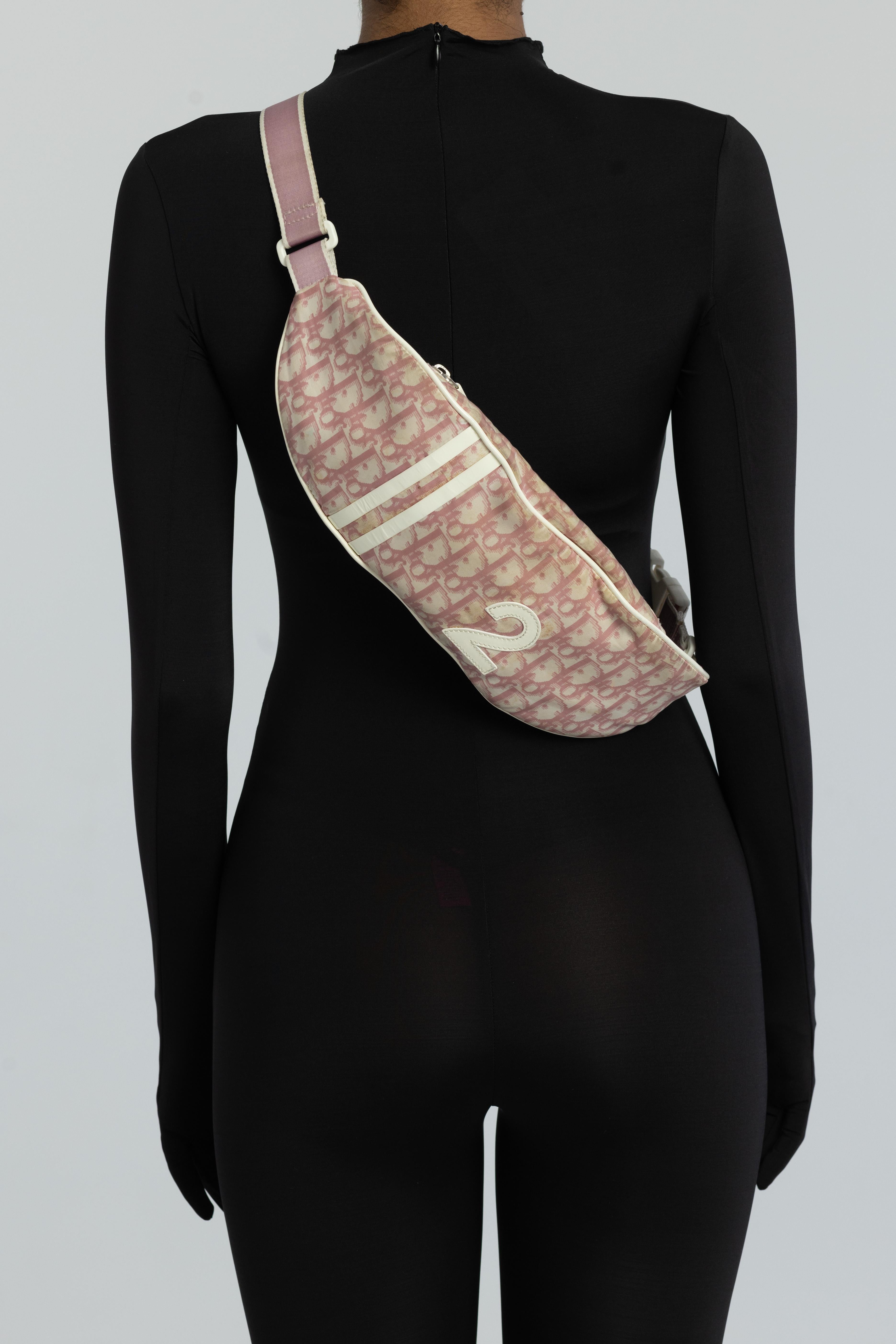 John Galliano for Dior, 2004. This Dior belt bag features diorissimo/trotter monogram print with white patent leather finishes including appliqué No 2 at front, dual front stripes and piping. The bag is finished with zip closure that opens to a pink