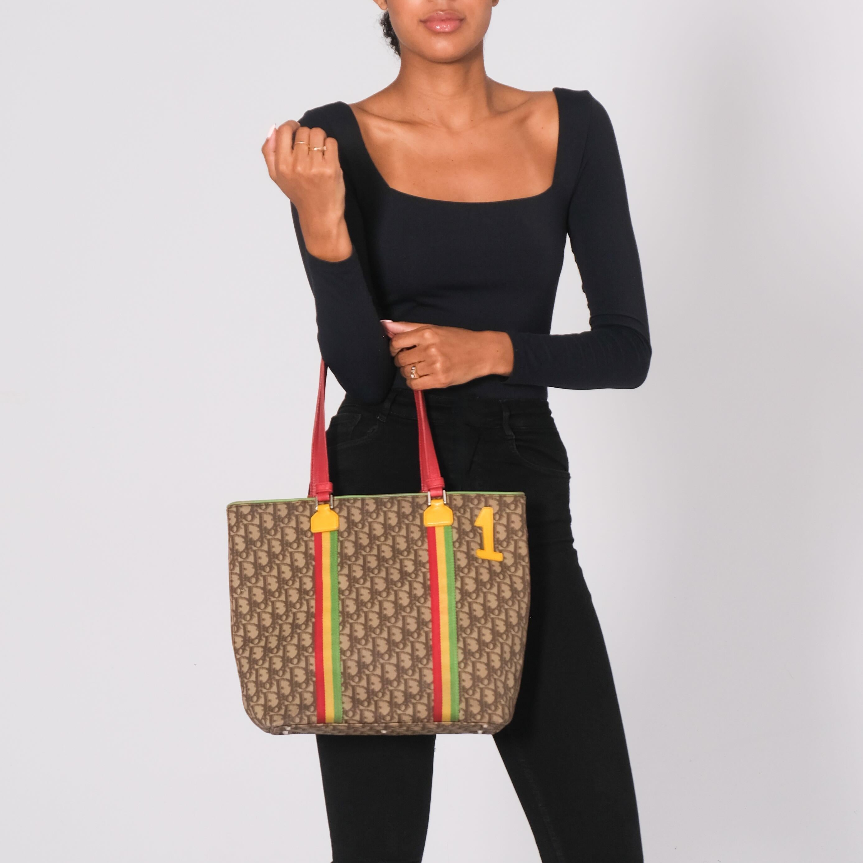 This Dior tote bag from the 2004 Rasta Collection by John Galliano is influenced by Jamaican culture. Crafted from coated canvas with an oblique monogram print in beige, it features the number 1 on the front and leather details in Rasta colors. The
