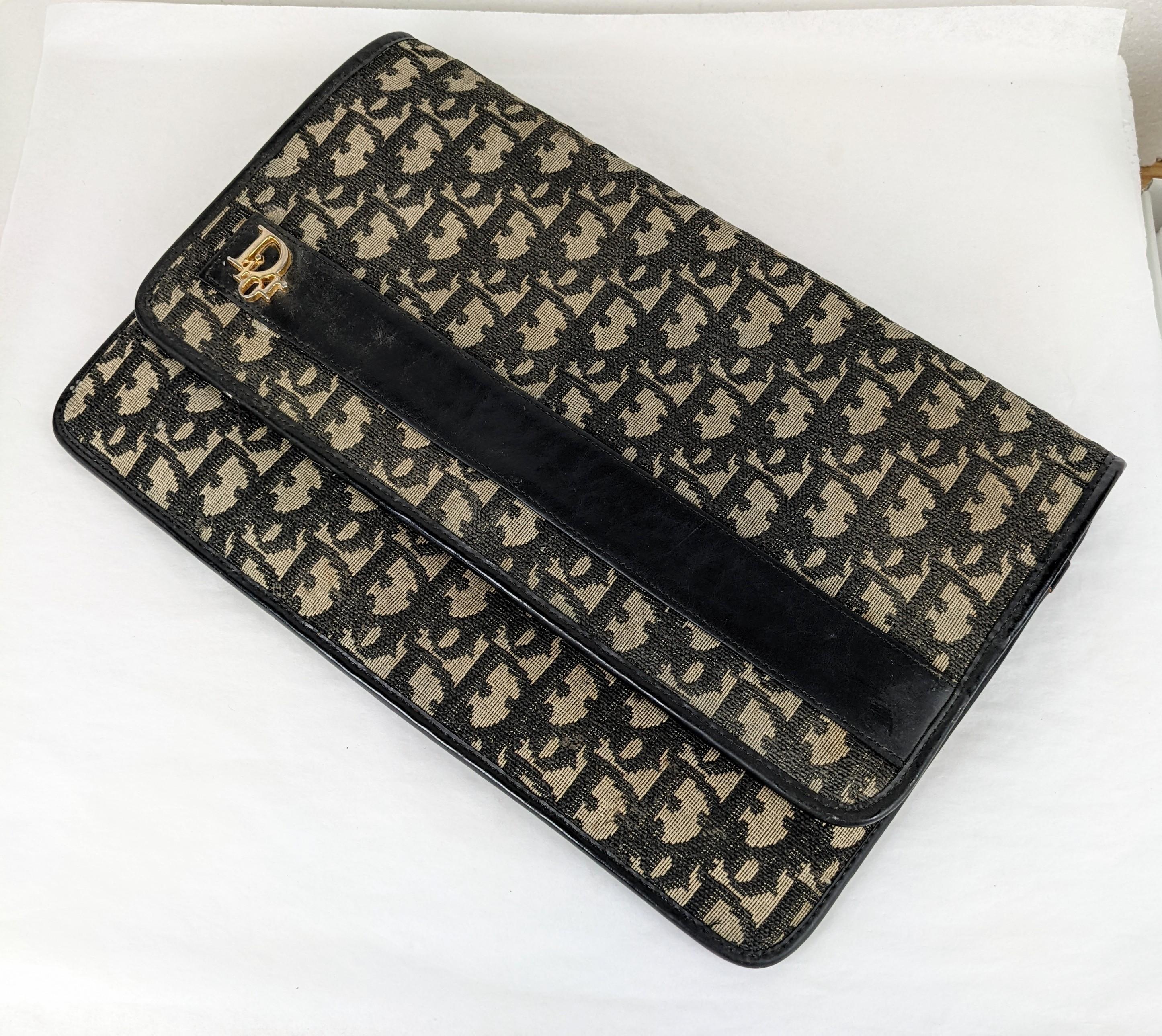 Dior Monogramme Oblique Vintage Clutch completely lined in navy calf leather. The main compartment is leather lined, there is a zippered pocket (unlined) on front. 
Snap closure is frozen so works as a foldover only can likely be released by a