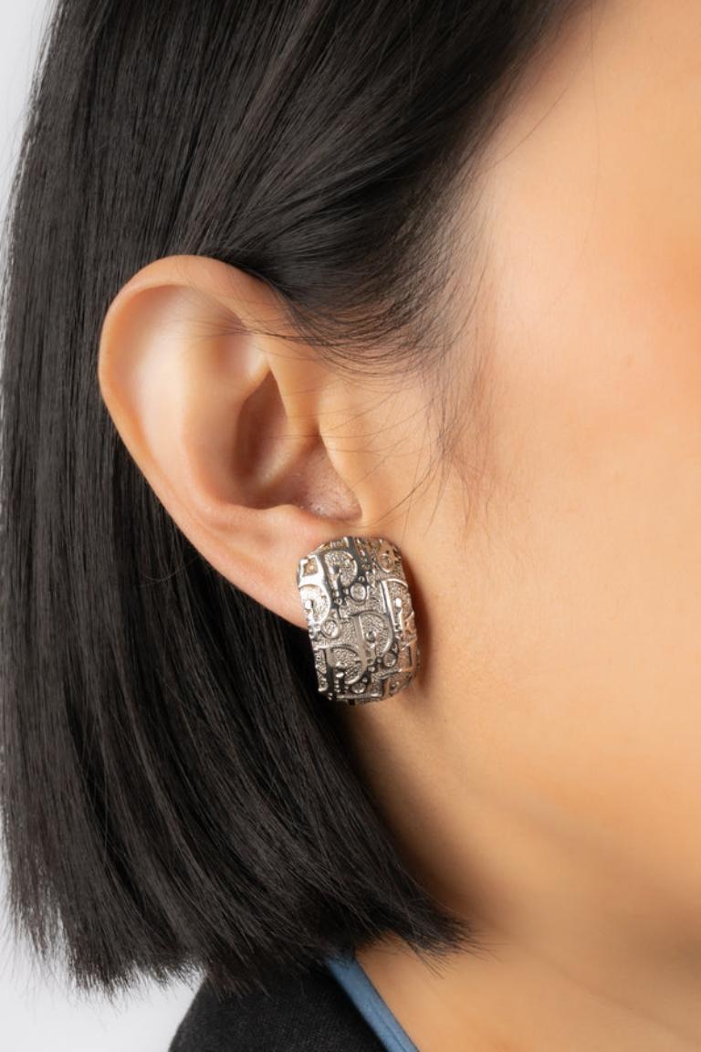 Dior - Silberne Ohrringe mit Monogrammen aus Metall zum Anstecken. Schmuckstücke, die unter der künstlerischen Leitung von John Galliano entstanden sind.

Zusätzliche Informationen: 
Zustand: Sehr guter Zustand
Abmessungen: 1,5 cm x 2,6 cm

Referenz