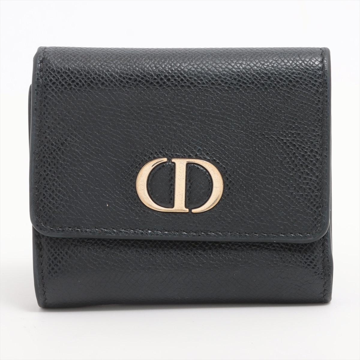 Die Dior Montaigne Trifold Geldbörse aus Leder in Schwarz ist ein elegantes und raffiniertes Accessoire, das das zeitlose Design von Dior widerspiegelt. Das Portemonnaie ist aus schwarzem Glattleder gefertigt und zeichnet sich durch eine