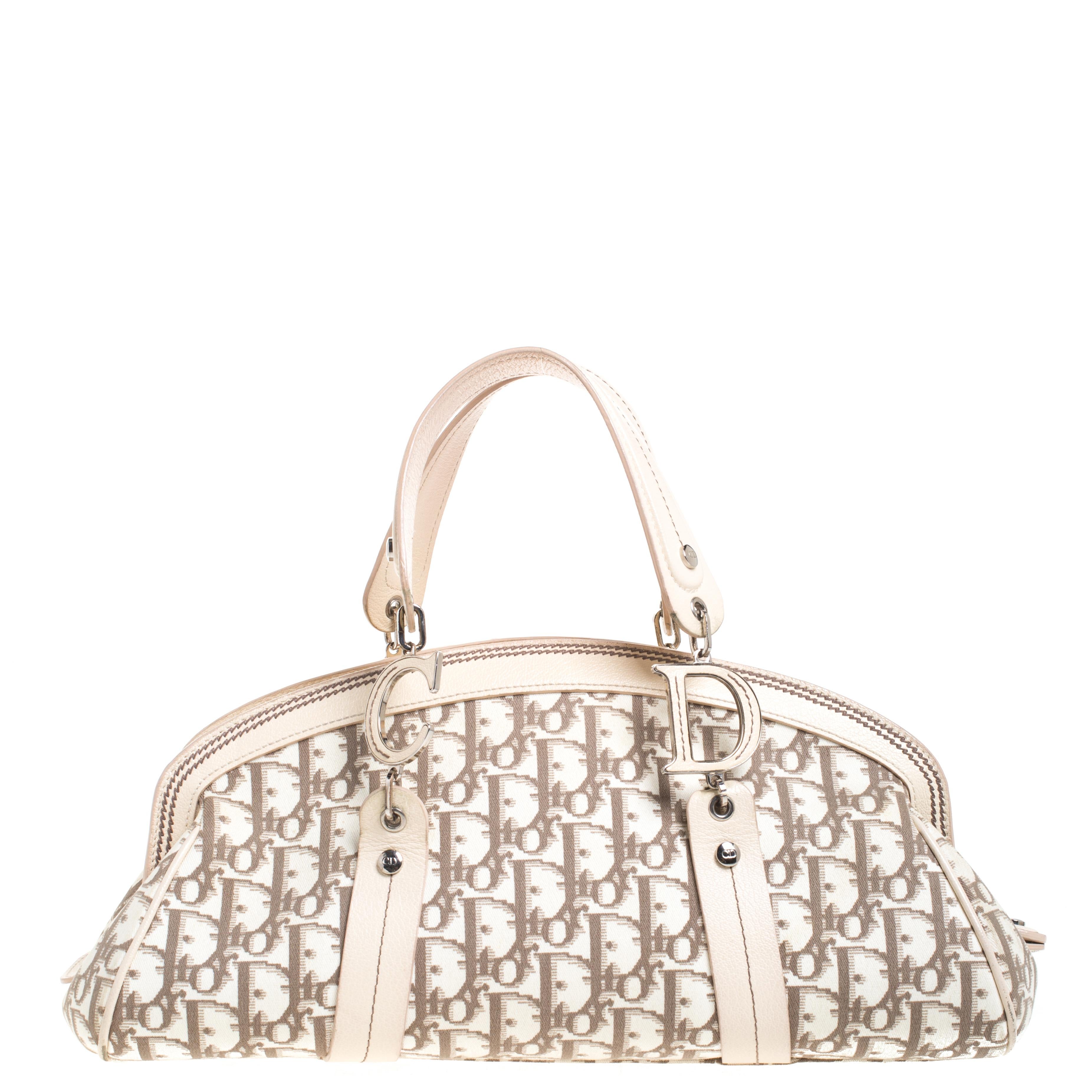 Start the summer season in style when you carry this adorable bag by Dior. It is crafted from signature Diorissimo fabric and leather trims. This satchel is accented with colorful floral embroidery on the front, silver-tone hardware and short