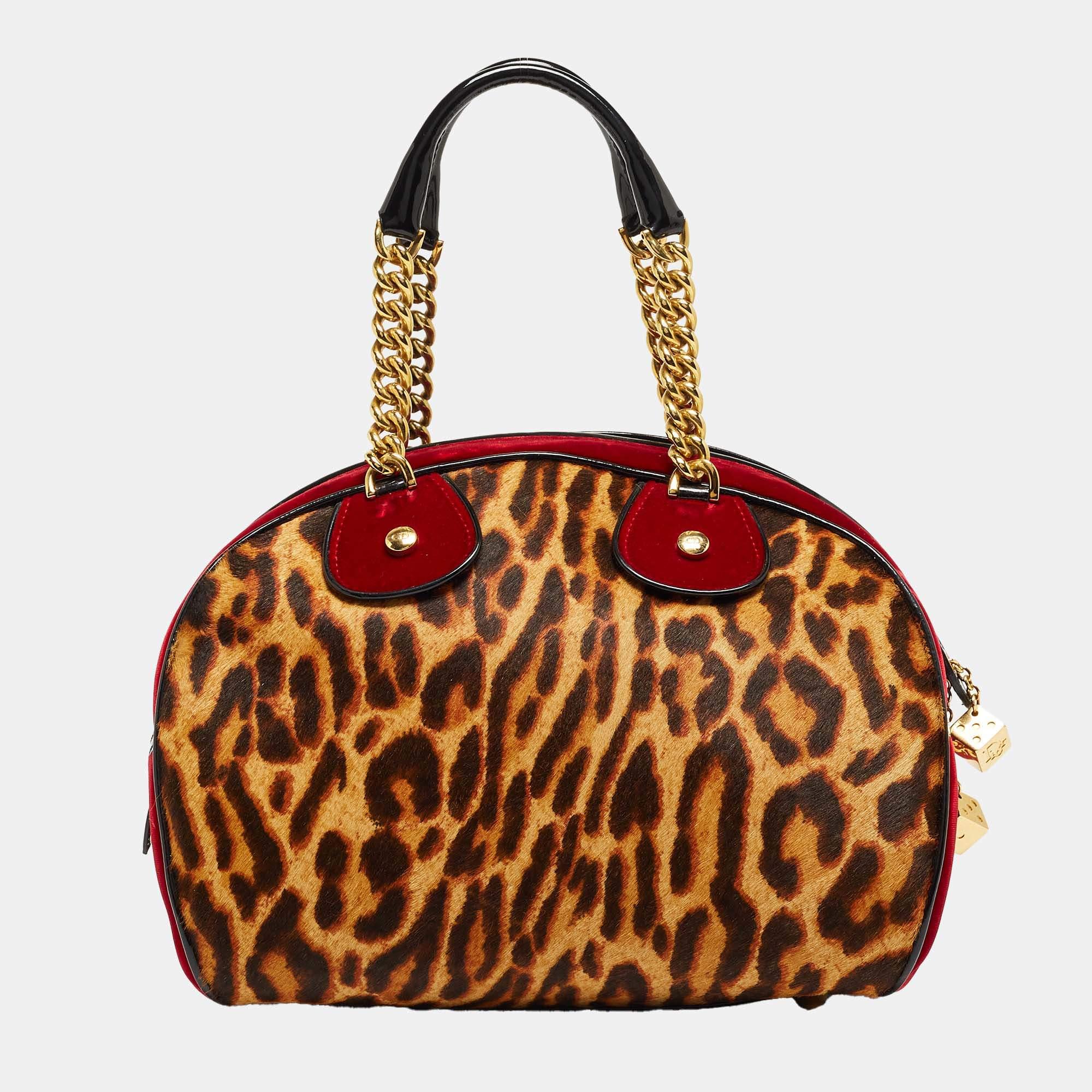 Spacious and stylish, this Gambler Dice bag is an offering by Dior. It has been crafted from leopard-printed calfhair, velvet as well as patent leather, and designed with dangling DIOR metal dice and two chainlink handles. The nylon interior will