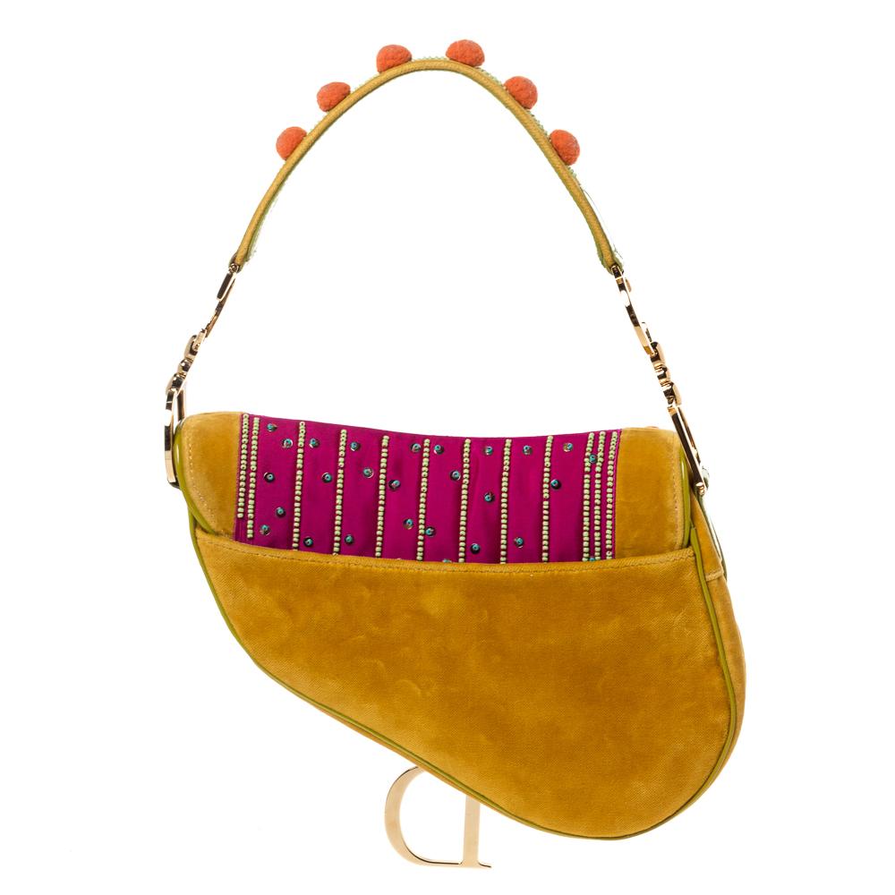Originally designed by John Galliano, the Dior Saddle bag made a smashing comeback in the year 2018. Here, we have a splendid version of the bag. It is made from velvet, nylon and patent leather and embellished with pom-poms. A single handle and a