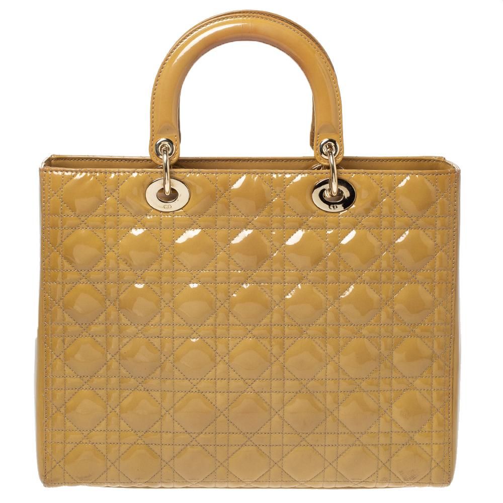 El bolso tote Lady Dior es una creación de Dior que ha ganado reconocimiento en todo el mundo y es hoy un bolso codiciado que toda fashionista ansía poseer. Este bolso tote mostaza se ha confeccionado en charol y lleva el característico acolchado