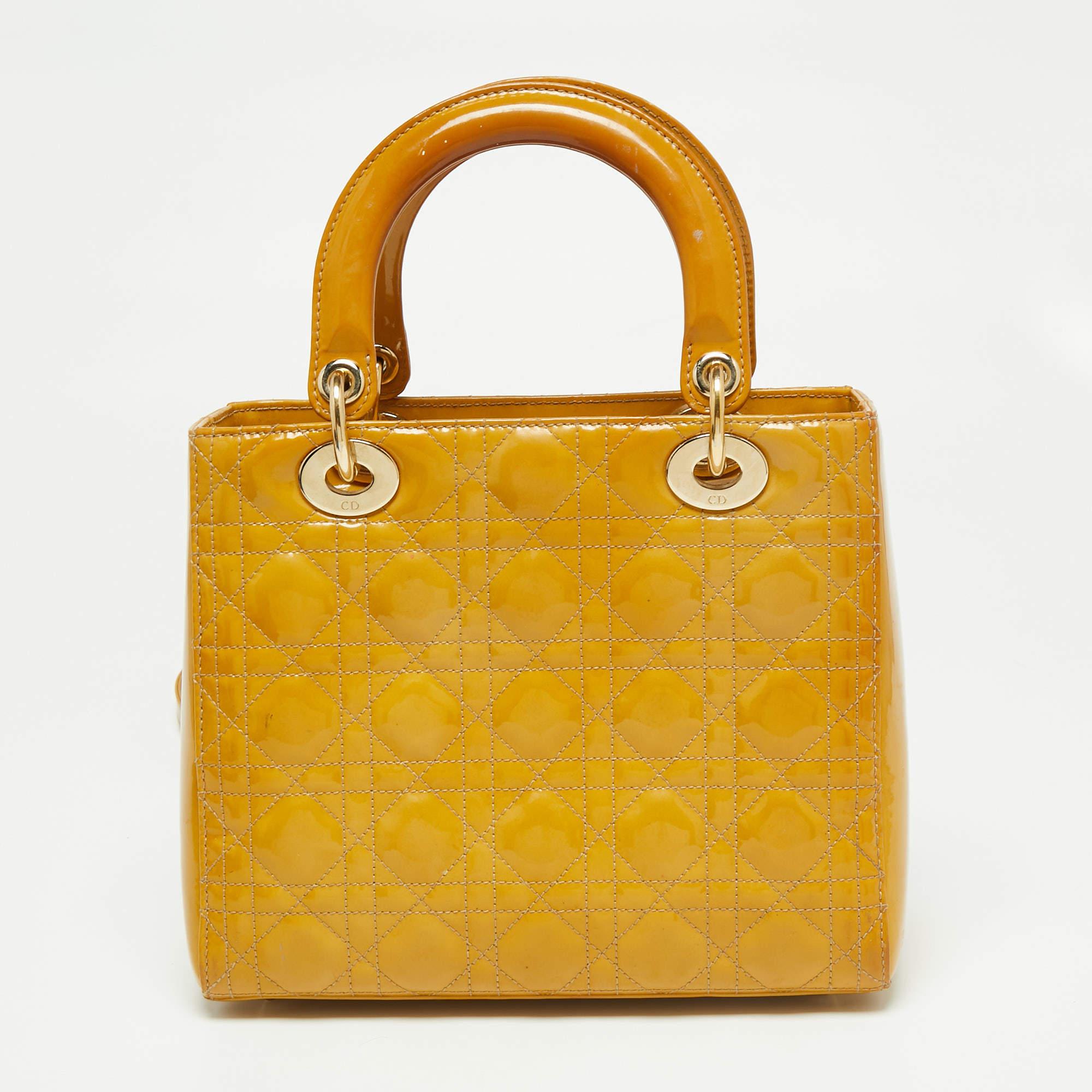 The Lady Dior tote is a Dior creation that has gained wide recognition and is a coveted bag that every fashionista craves to possess. The mustard tote has been crafted from patent leather and carries the signature Cannage quilt. It is equipped with