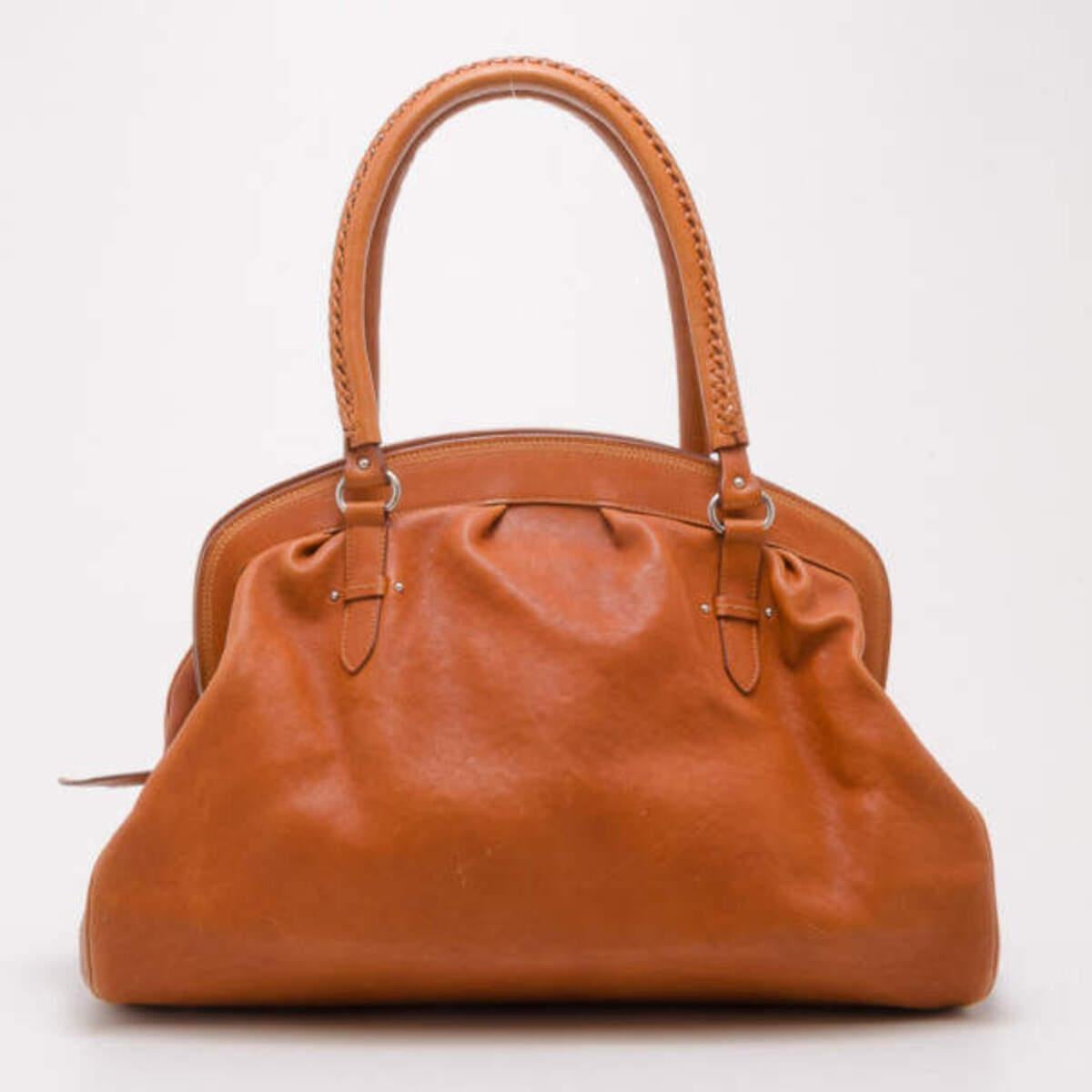 With its versatile color and classic shape, this satchel by Dior makes for a great everyday handbag. Made from smooth tan leather, the exterior features two front pockets, a Dior motif and double handles with bold stitching. Its large leather lined