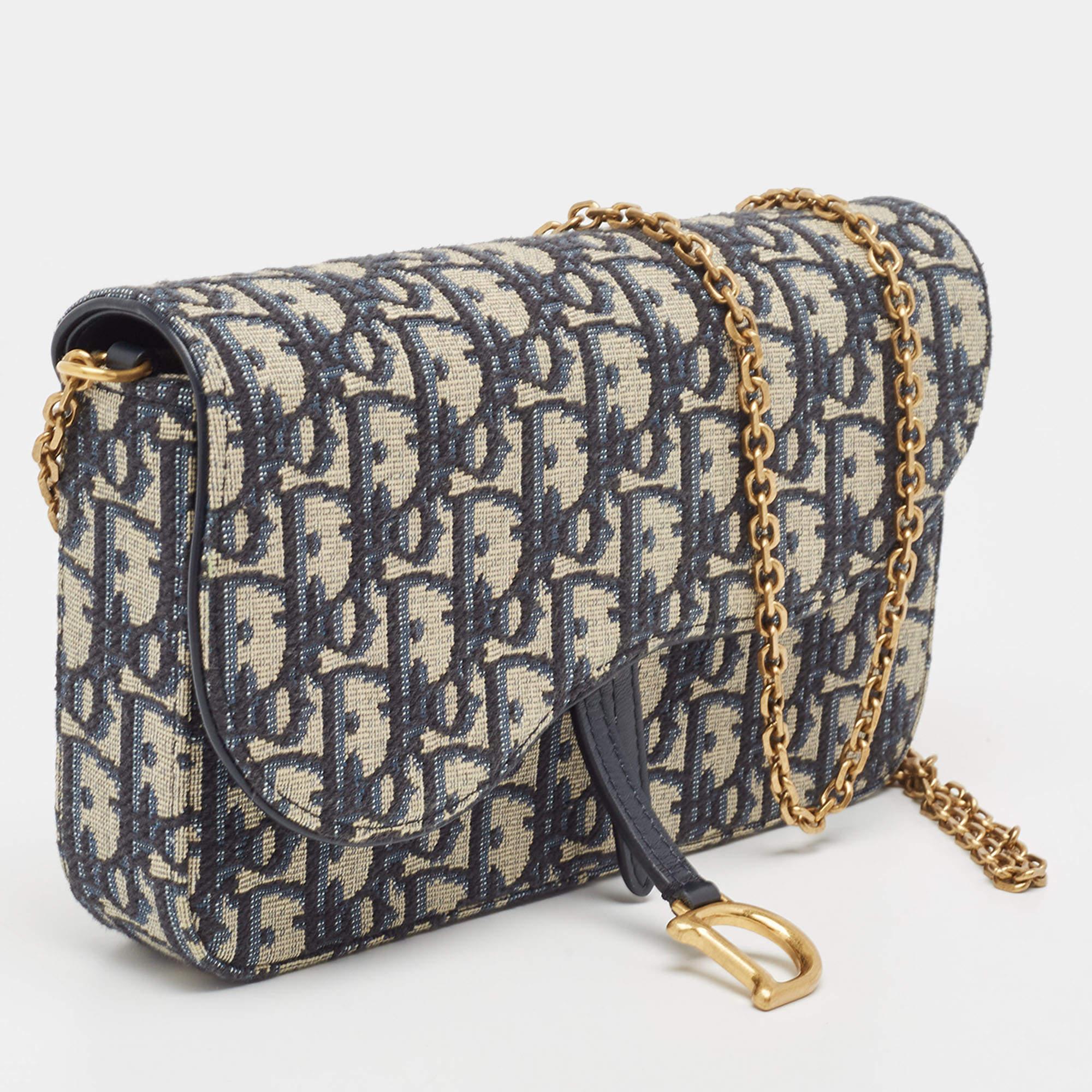 Designed to be carried as a shoulder bag, crossbody bag, or clutch, this Saddle pouch by Dior speaks of all things fashionable. It is made from Oblique canvas and designed in the likeness of the brand's famous Saddle bag. The bag has a removable