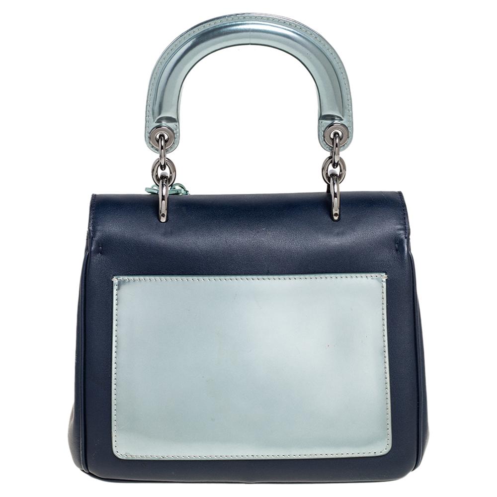This mini Be Dior bag from the House of Dior is sure to add sparks of luxury to your wardrobe! It is crafted using navy-blue, metallic mint green leather on the exterior, with the D.I.O.R charms embellishing the front. It has dual handles,