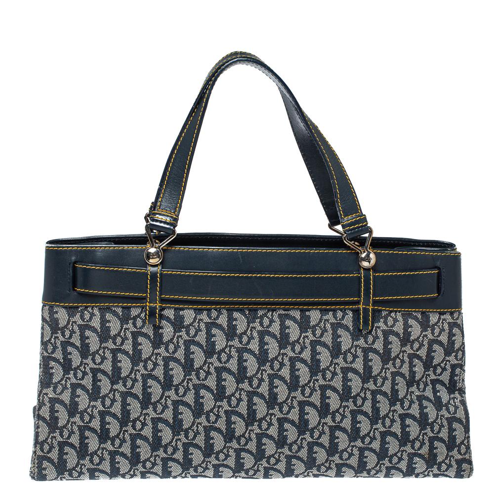 This vintage Dior tote is perfect for a host of occasions. It has been crafted from the brand's signature oblique denim and leather. With a navy blue hue, it comes with dual handles, buckle detailing in the front, silver-tone hardware and a spacious