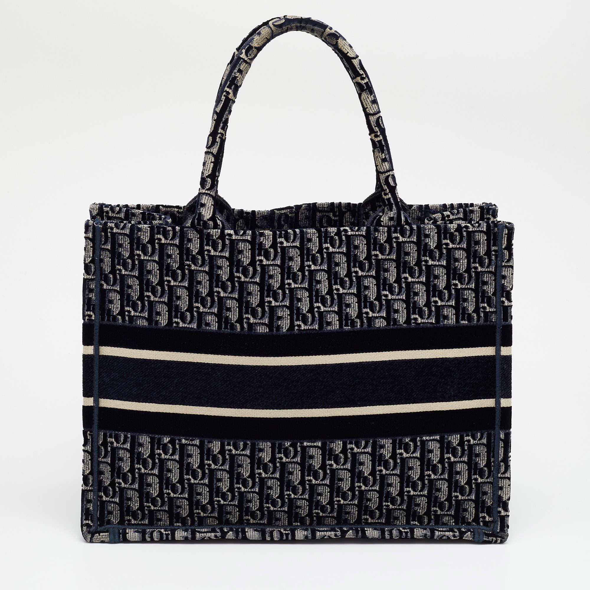 Maria Grazia Chiuri, Art Director of Dior, introduced to the world a functional style blended with signature aesthetics through this fabulous Book tote. Fully embroidered in navy-blue Oblique Monogram velvet, this tote is autographed with the iconic