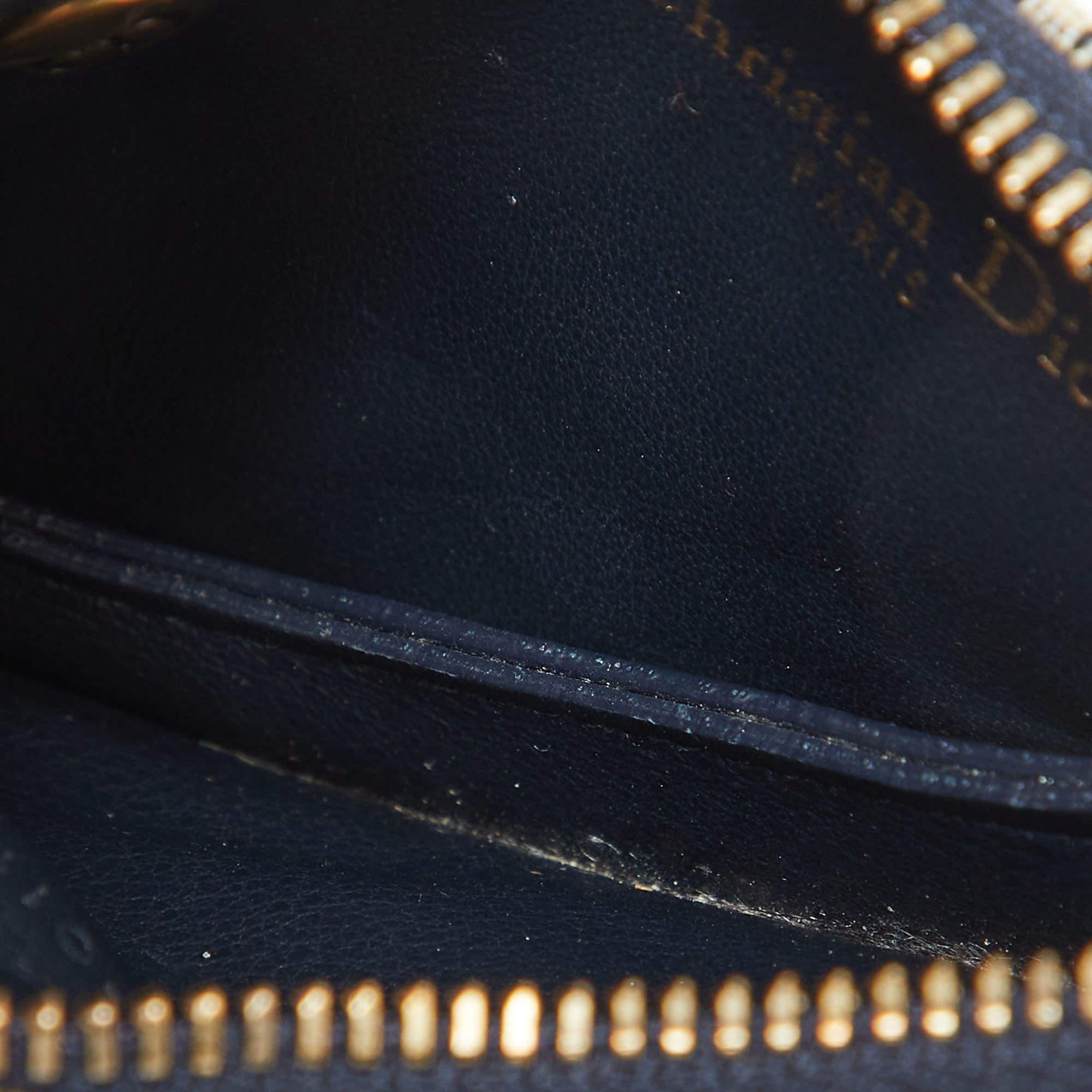 Designed in the famous Saddle shape  this Dior coin purse is made from fabric coated with the signature Oblique print in a navy blue hue. The exterior is detailed with a gold tone D charm. The zip closure opens to a leather lined interior for you to