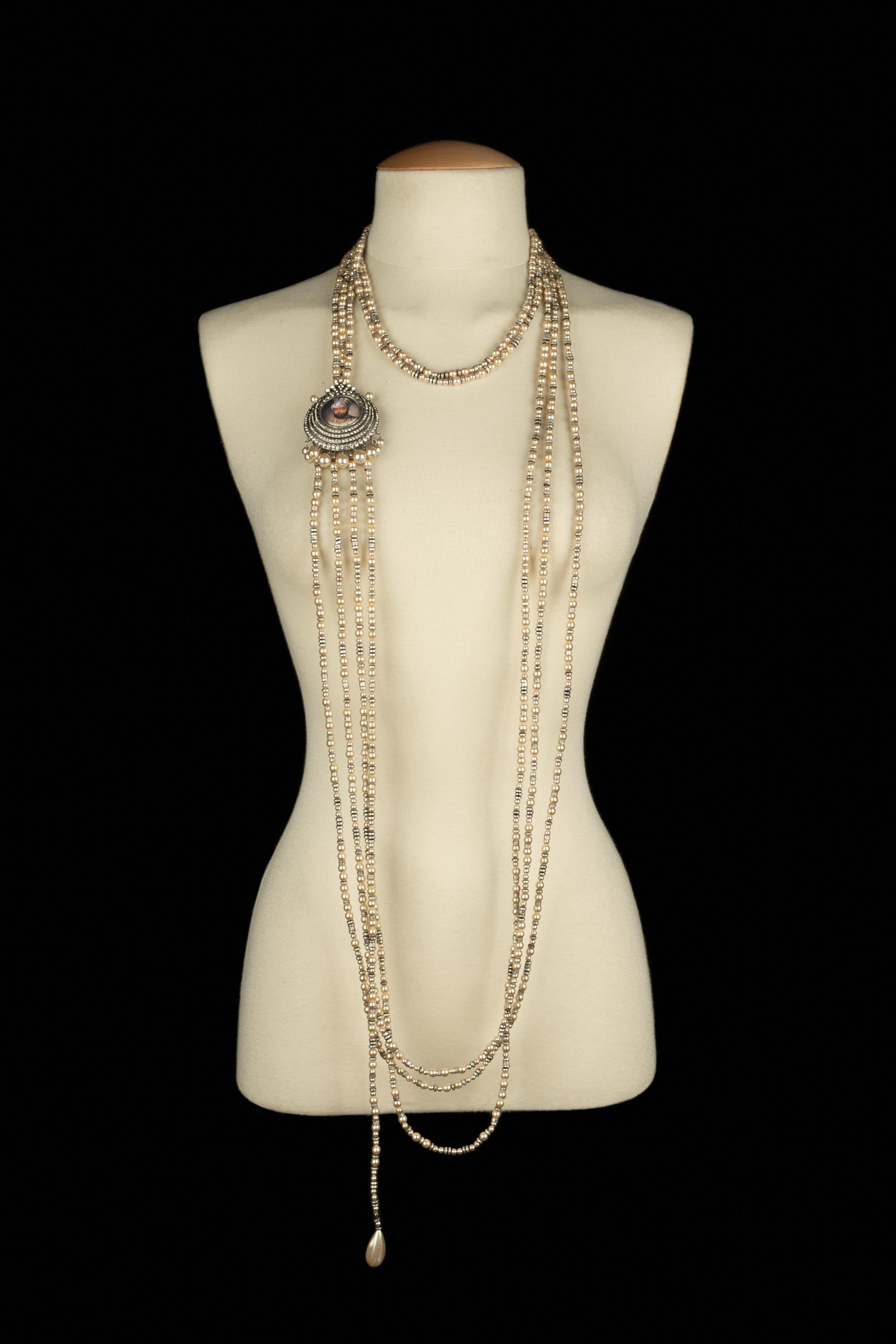DIOR - (Fabriqué en France) Rare collier sautoir à plusieurs rangs de perles fantaisie en ivoire intercalées d'éléments en métal argenté antique et d'un médaillon broche portrait à l'indienne. Signature sur une assiette. Collection 