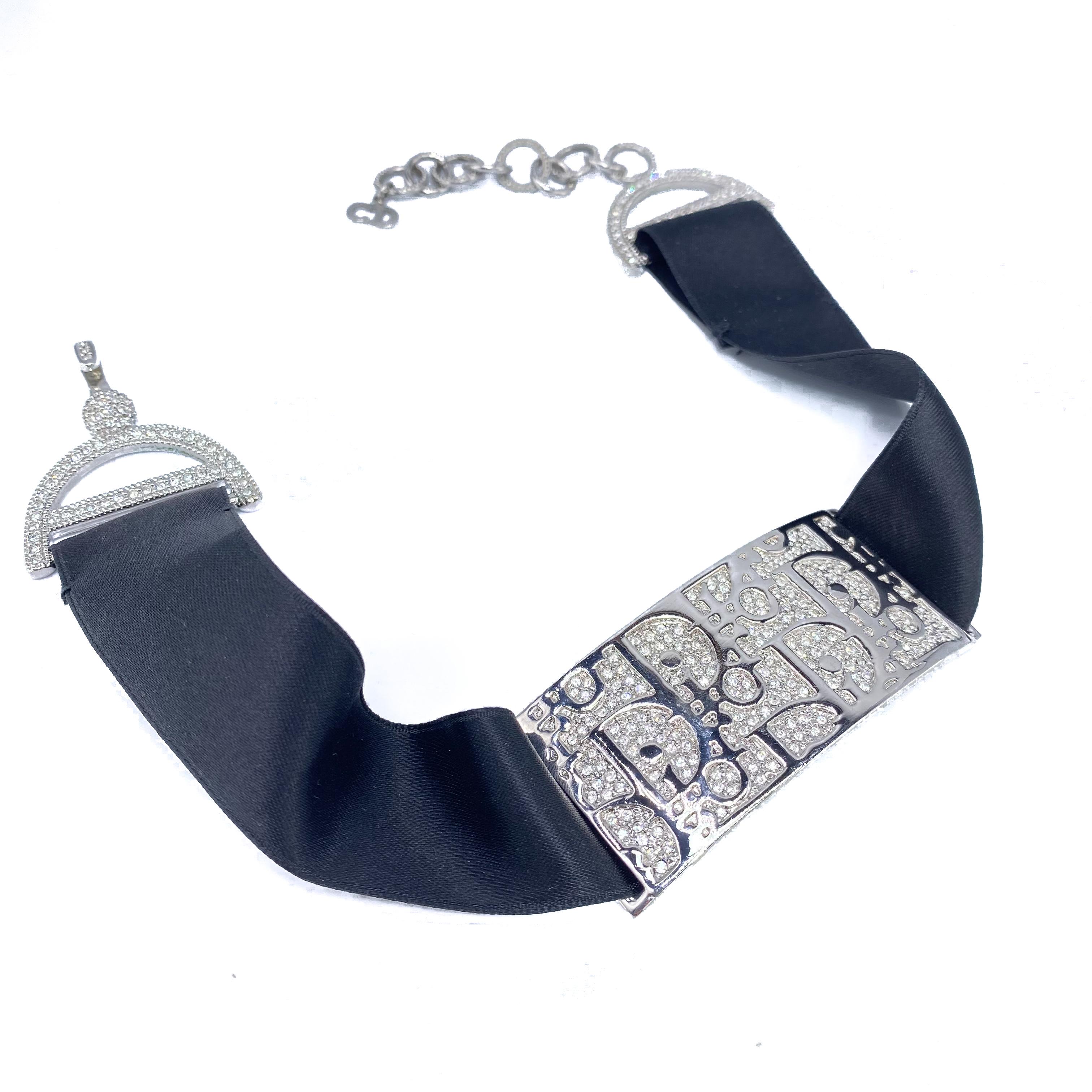 Dior Y2K Vintage Trotter Choker 

An incredible statement piece from the late 90s Dior archive

Detail
-Rectangular pendant crafted from rhodium silver metal featuring the iconic trotter logo pattern
-Black satin ribbon choker
-Rhinestone encrusted