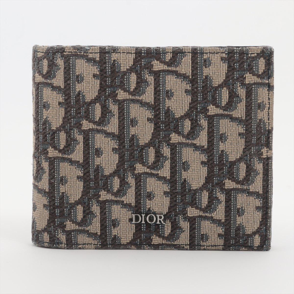 The Dior Oblique Canvas Leather Bi-fold Wallet in Navy Blue is a sophisticated and timeless accessory that showcases Dior's iconic design elements. Crafted from durable canvas and adorned with the signature Oblique monogram pattern, the wallet