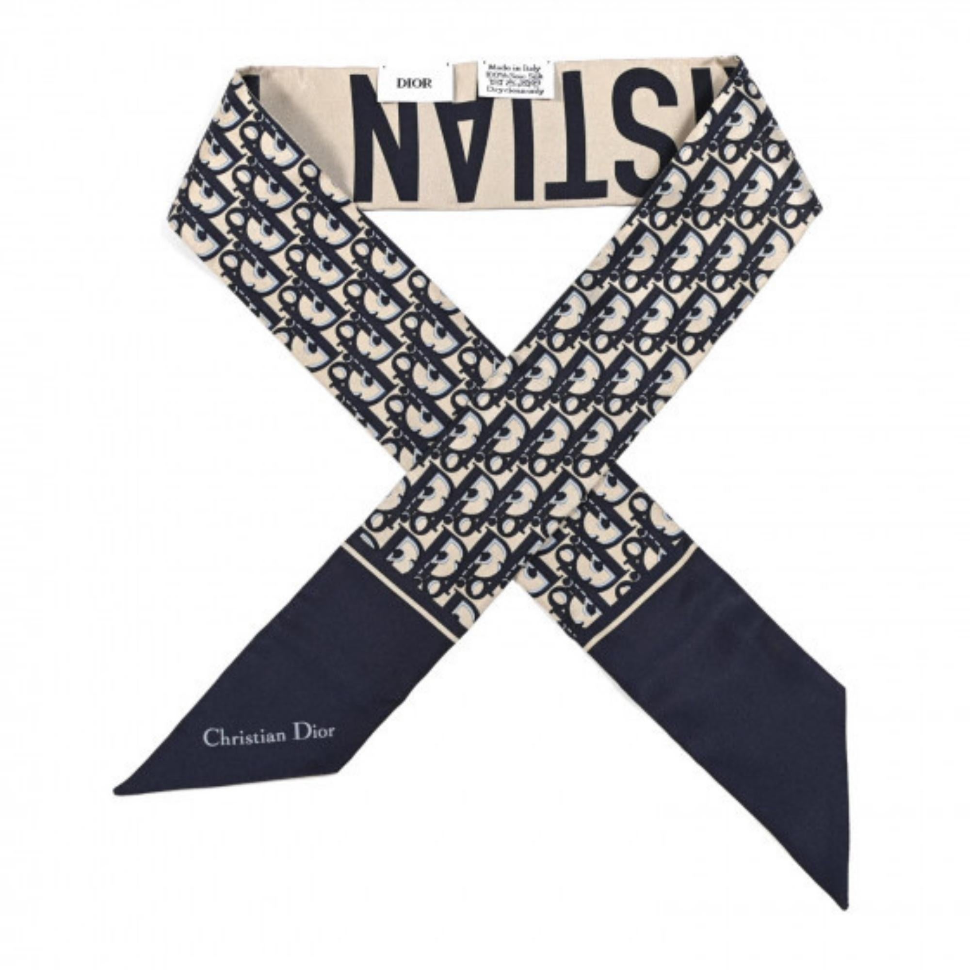 The Dior Oblique Mitzah scarf highlights the House's iconic motif dating back to 1967. Made in navy blue silk twill, it is distinguished by an elongated shape with pointed ends and is embellished with a 'CHRISTIAN DIOR' signature on the back. The