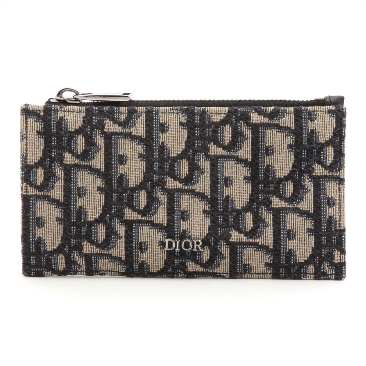 The Dior Oblique Zipped Card Holder in Black x Navy is a sleek and sophisticated accessory that combines style with practicality. Crafted from high-quality canvas adorned with the iconic Dior Oblique pattern, the card holder exudes luxury and