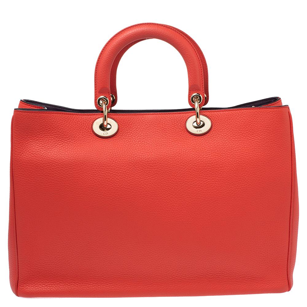 The Diorissimo shopper tote from Dior is a piece that has never gone out of style. The leather bag comes in a pleasing orange shade with gold-tone hardware and Dior letter charms. It features two top handles, protective feet at the bottom, and an