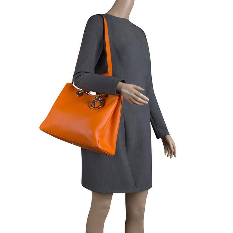 Die Diorissimo Tasche von Dior ist ein Stück, das nie aus der Mode gekommen ist. Die Ledertasche ist in einem verführerischen Orangeton gehalten und mit silberfarbenen Beschlägen und Dior Buchstabencharme versehen. Sie verfügt über eine Tasche,