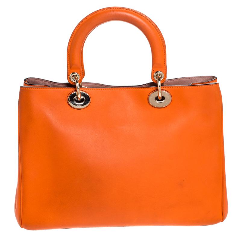 The Diorissimo shopper tote from Dior is a piece that has never gone out of style. The leather bag comes in an orange shade with gold-tone hardware and Dior letter charms. It features double top handles, a small pouch and protective feet at the