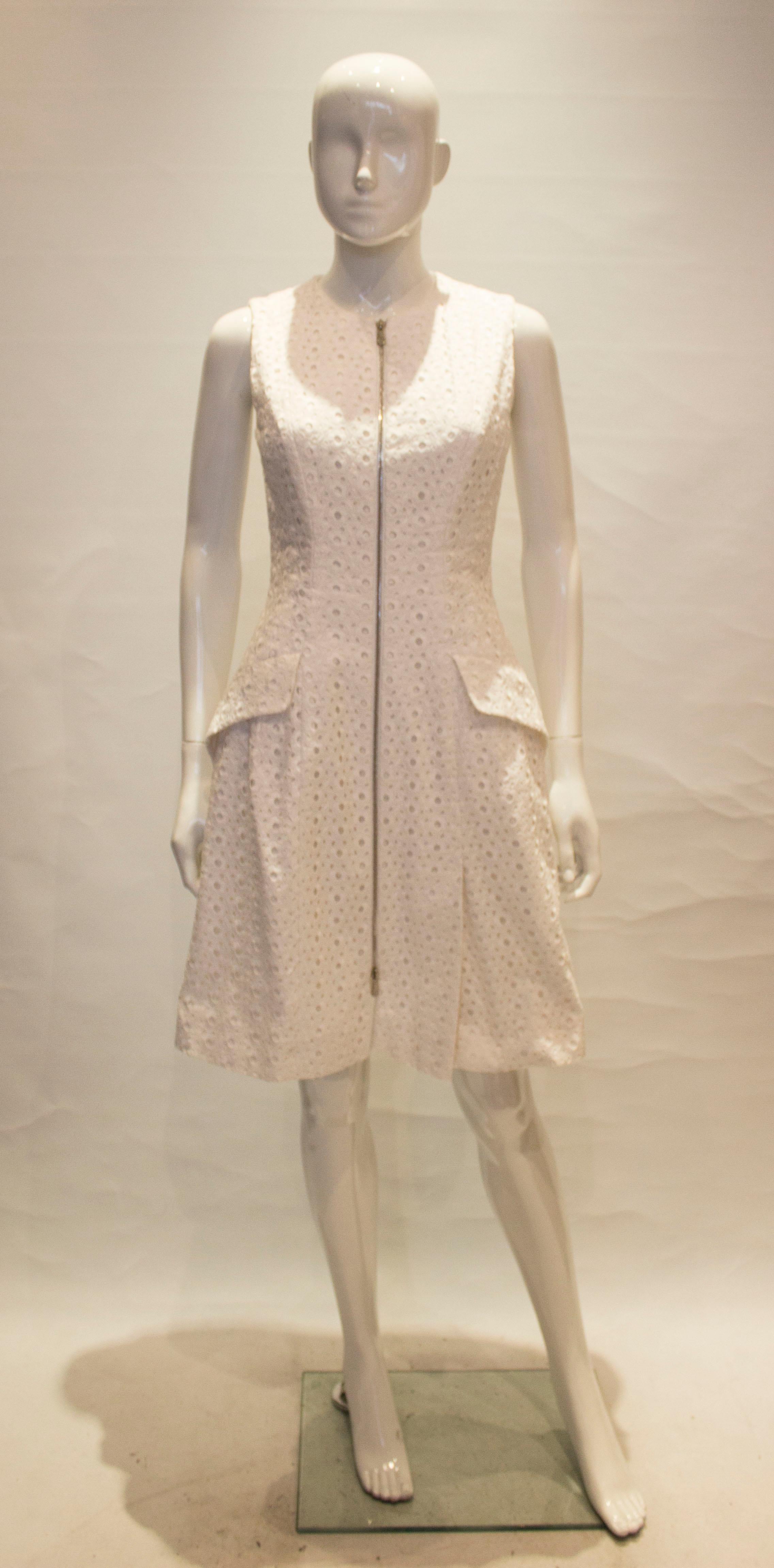 A great white dress by Dior Paris, in a heavy brorderie anglaise. The dress has a zip front opening and two pockets.  It is fully lined.