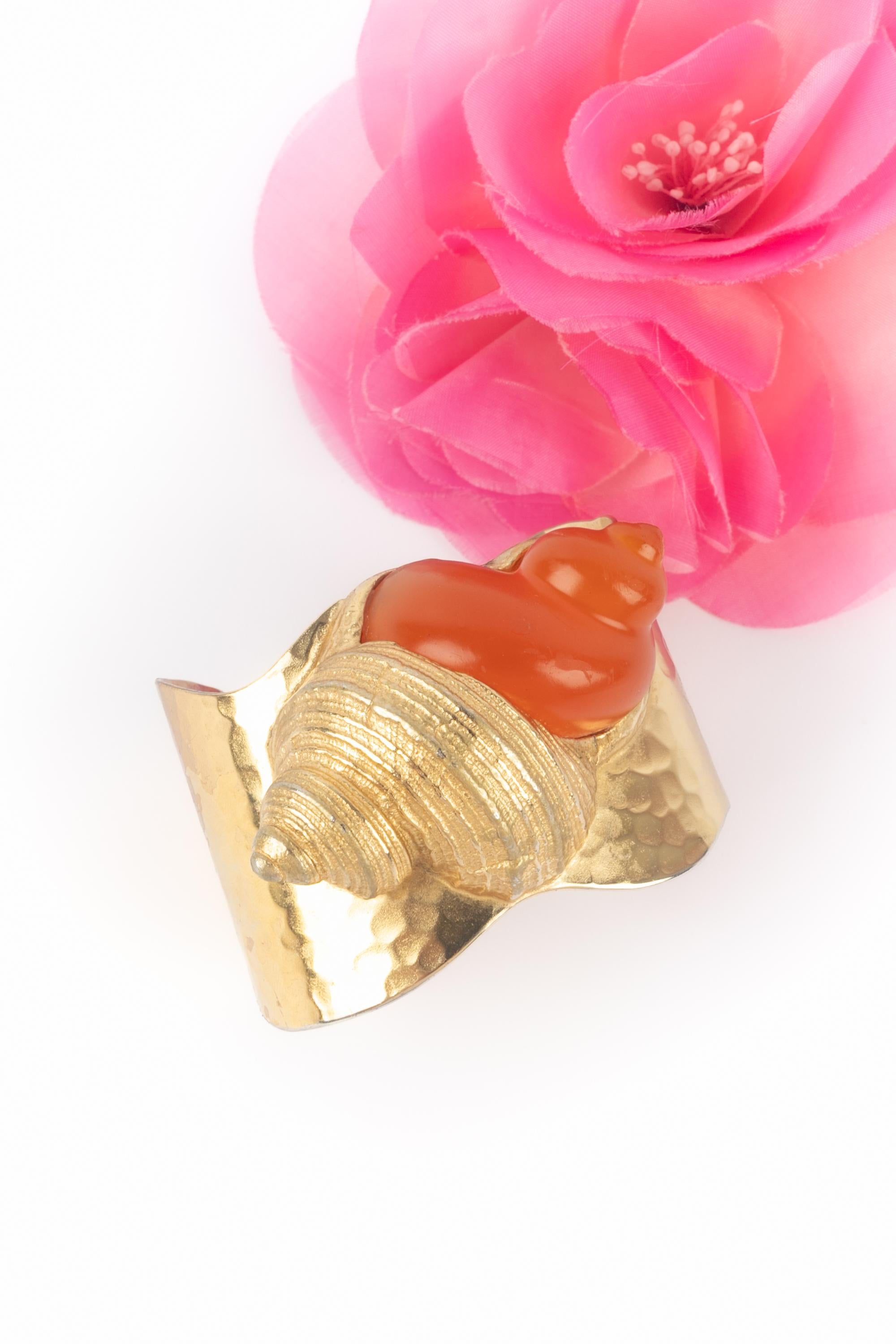 DIOR - (Made in France) Raro bracciale a conchiglia in metallo dorato con resina arancione. Gioielli disegnati dall'Atelier Goossens per la maison Dior in occasione dell'uscita del perdume Dune nel 1987.

Condizioni:
Buono