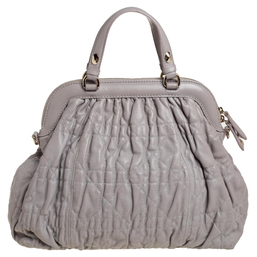 Stylish and elegant, this Delices bag by Dior is for modern women who enjoy a touch of old-world char,. Crafted from Cannage quilted leather, this pewter-grey bag has a framed silhouette. It comes with dual handles, a zip closure and gold-tone