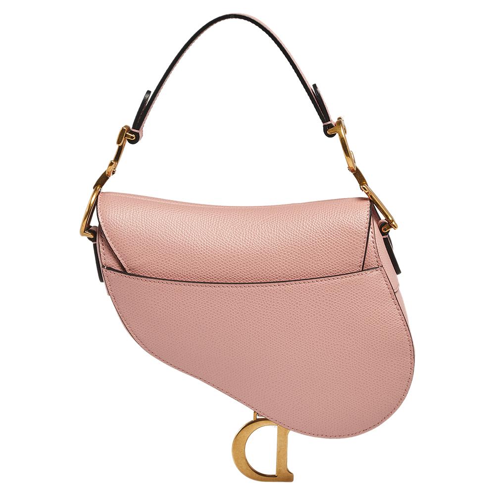An example of timeless style and great design ideas, Dior's Saddle bag is sought after for all the right reasons. This pink Saddle bag for women is crafted using grained leather in an iconic shape and it has gold-tone CD letters to hold the single